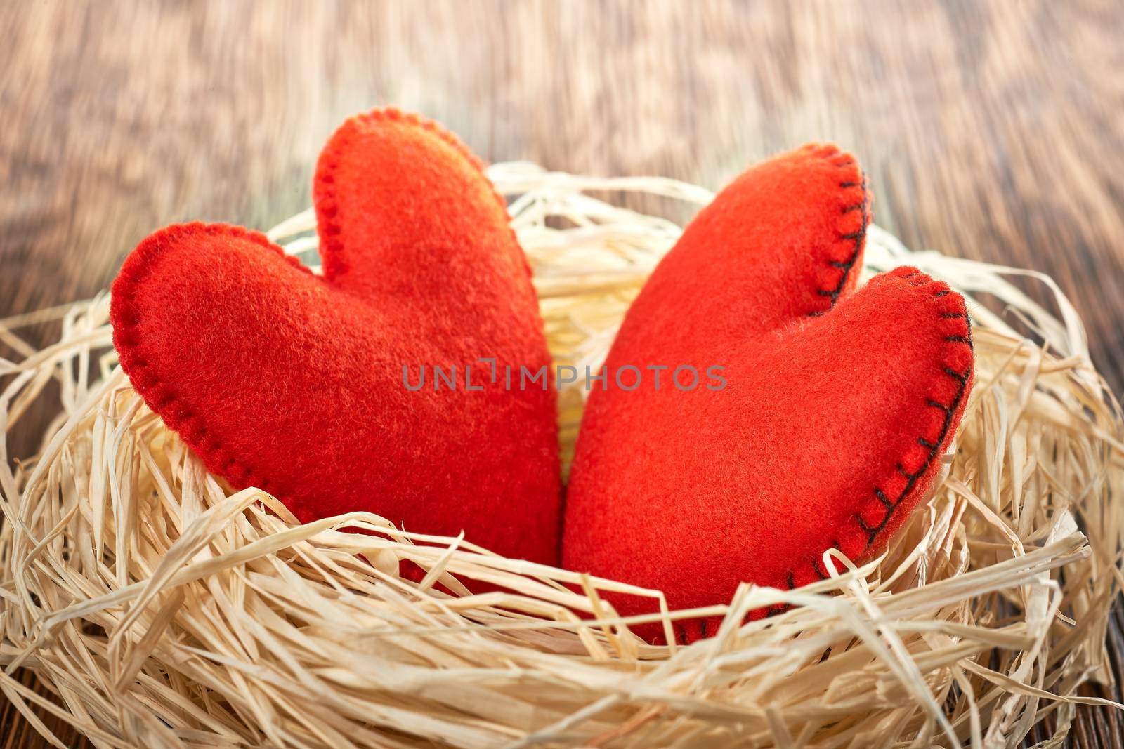 Love hearts, Valentines Day. Hearts handmade on wooden background. Couple made of red felt in straw nest. Vintage romantic style. Vivid greeting card.  