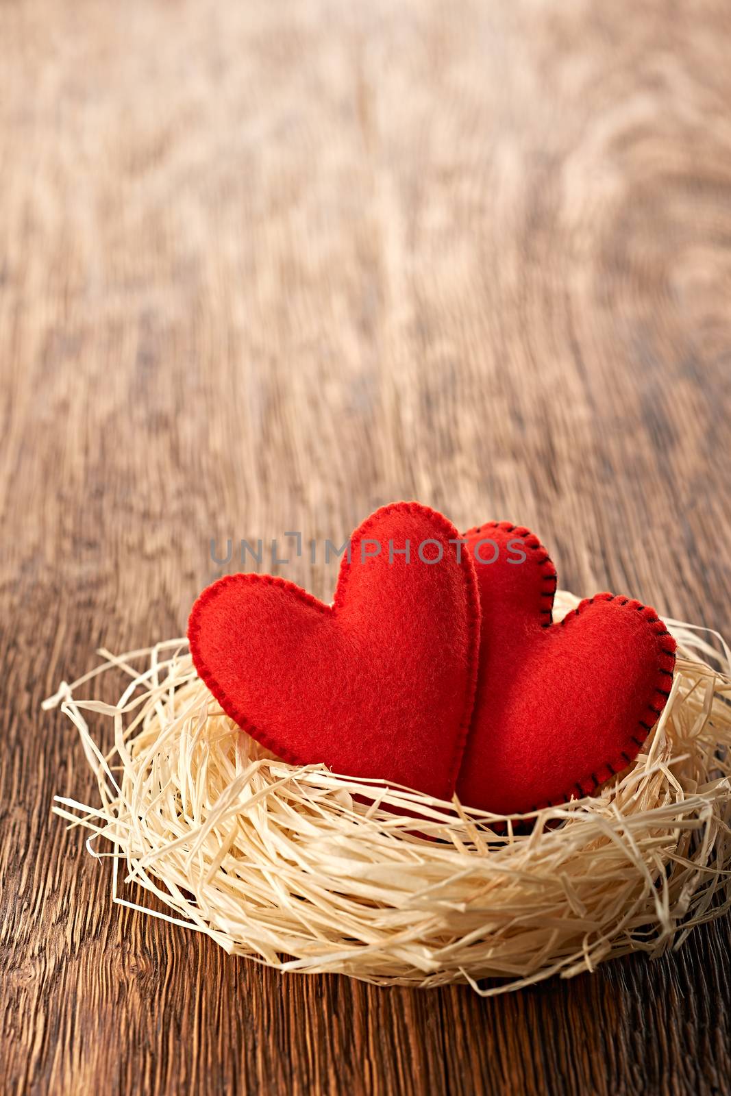 Love hearts, Valentines Day. Hearts handmade on wooden background. Couple made of red felt in straw nest. Vintage romantic style. Vivid greeting card, copyspace.  
