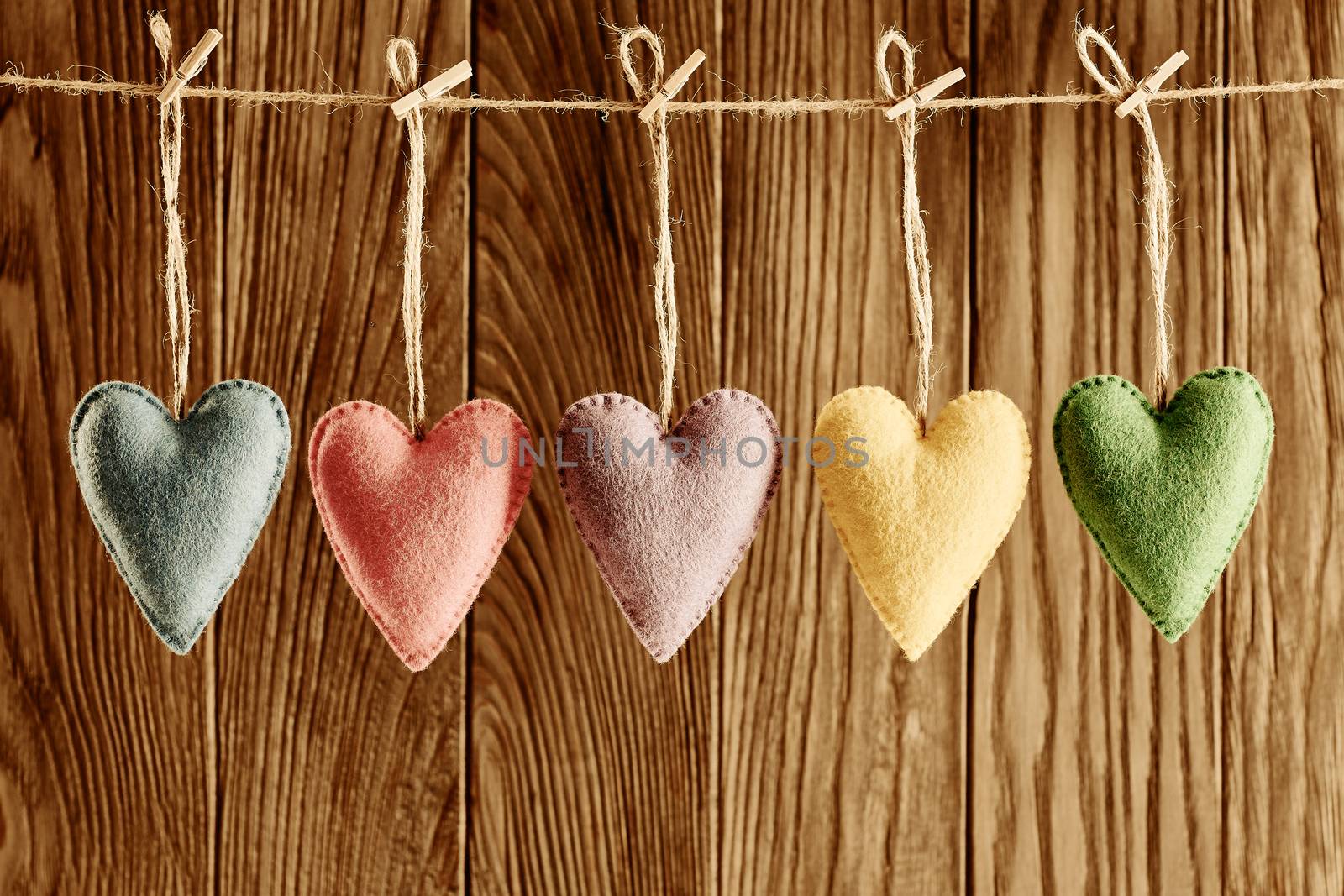 Love hearts, Valentines Day. Hearts set, handmade, hanging on rope. Vintage romantic style on wooden background. Vivid retro unusual greeting card, multicolored felt, toned, copyspace