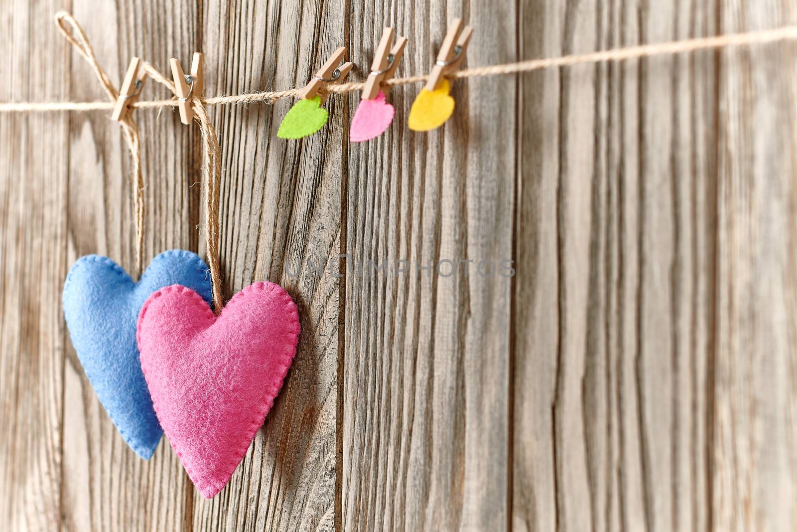 Love hearts, Valentines Day. Hearts couple, handmade, hanging on rope. Vintage romantic style on wooden background. Vivid unusual greeting card, multicolored felt, perspective, copyspace