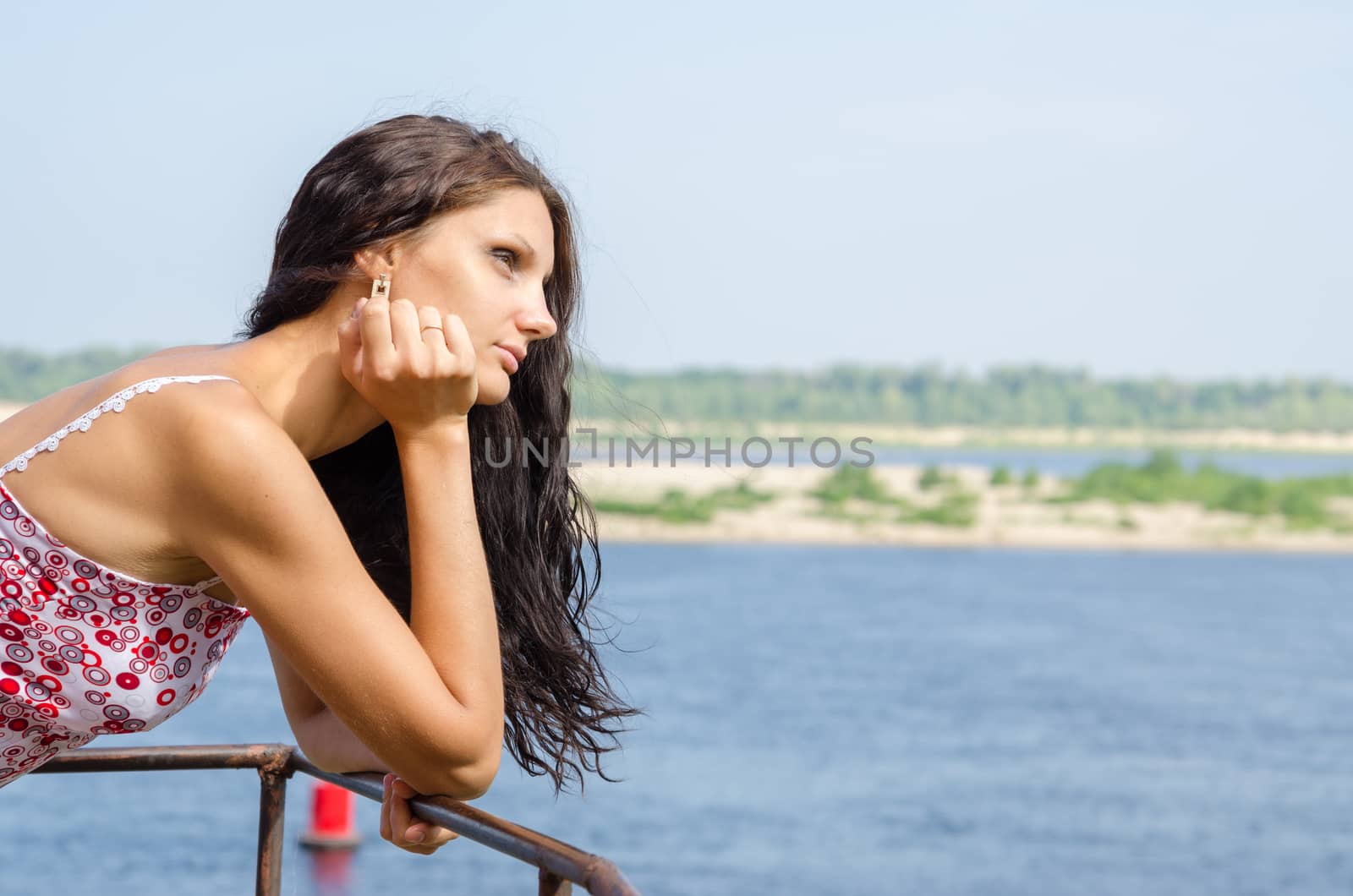 Young brunette girl looking thoughtfully into the distance on the background of the river