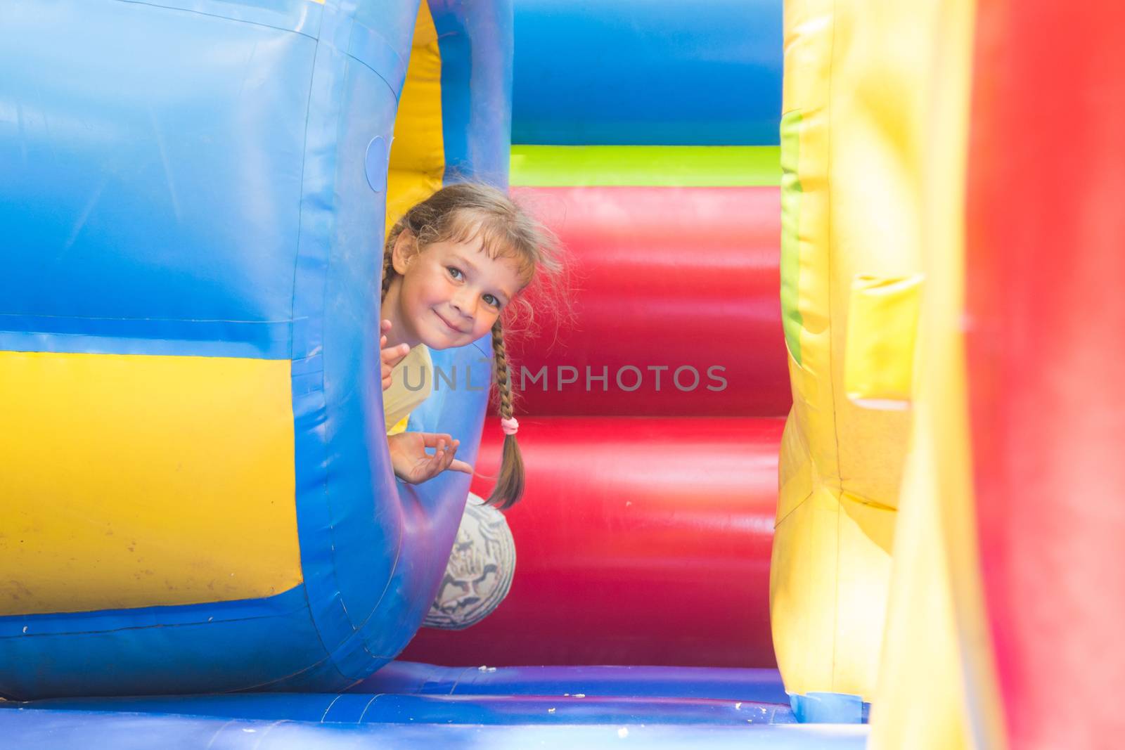 Happy little girl got out of the inflatable soft barrel while playing on the trampoline