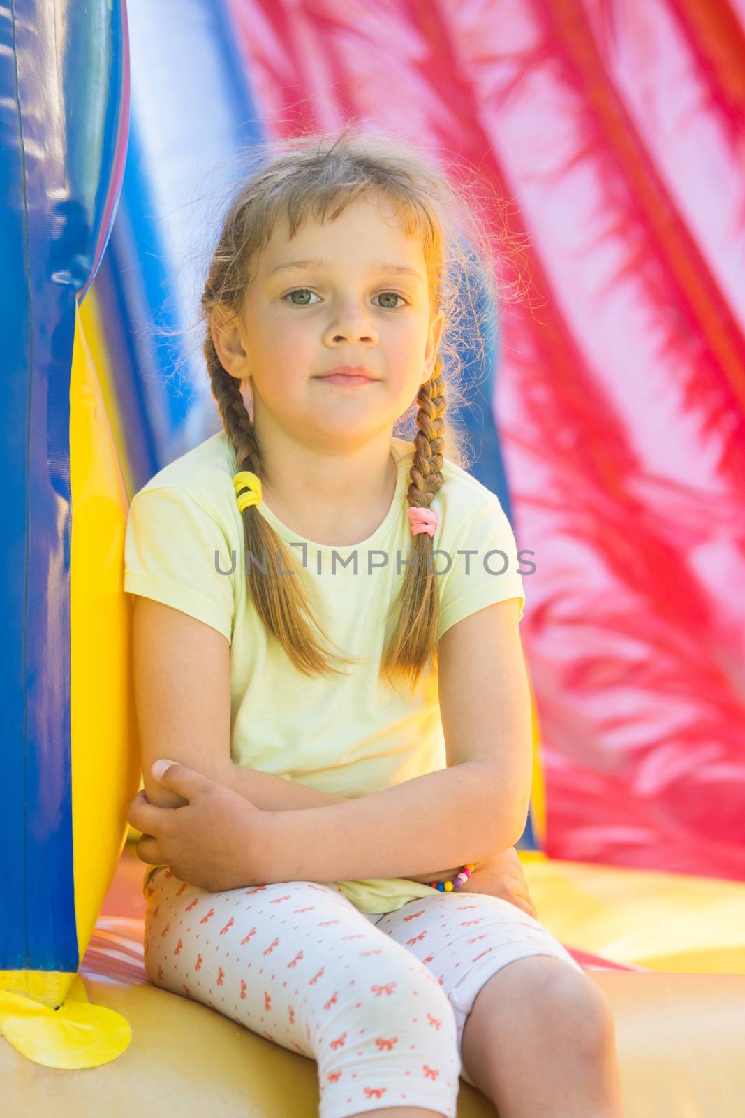 Five-year girl naprygalis on a large inflatable trampoline sat down to rest