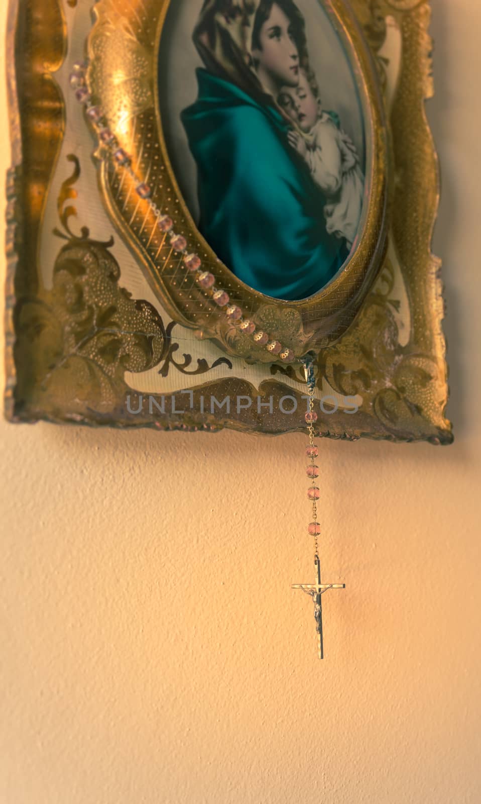 Hung on a painting an old rosary with crucifix on a light background,copy space.used split toning for vintage/old style.