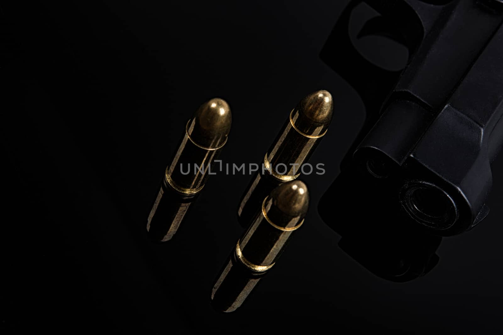 Gold bullets and gun on black background