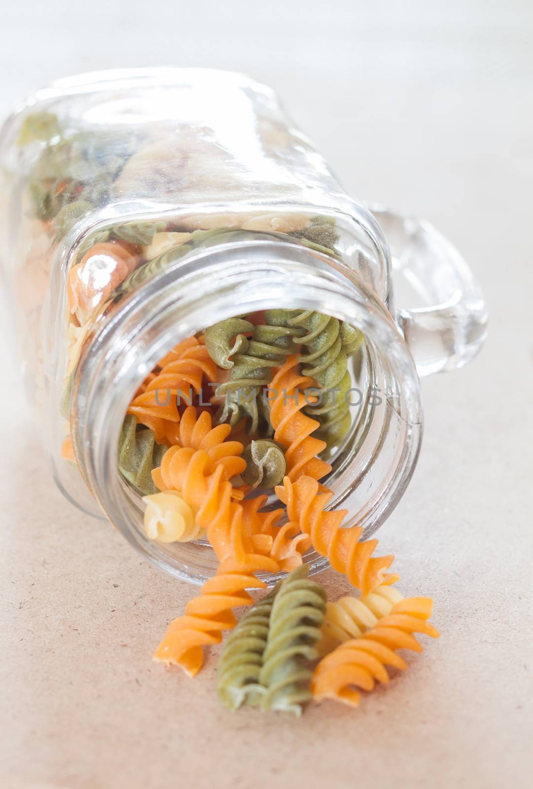 Raw fusilli pasta with glass bottle, stock photo