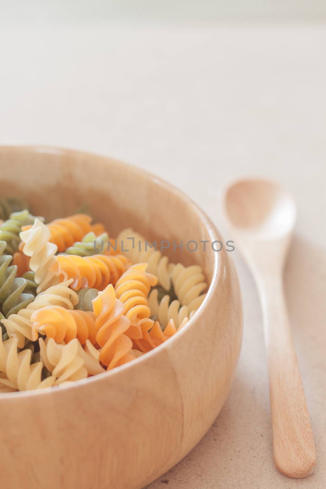 Raw fusilli pasta on wooden bowl, stock photo