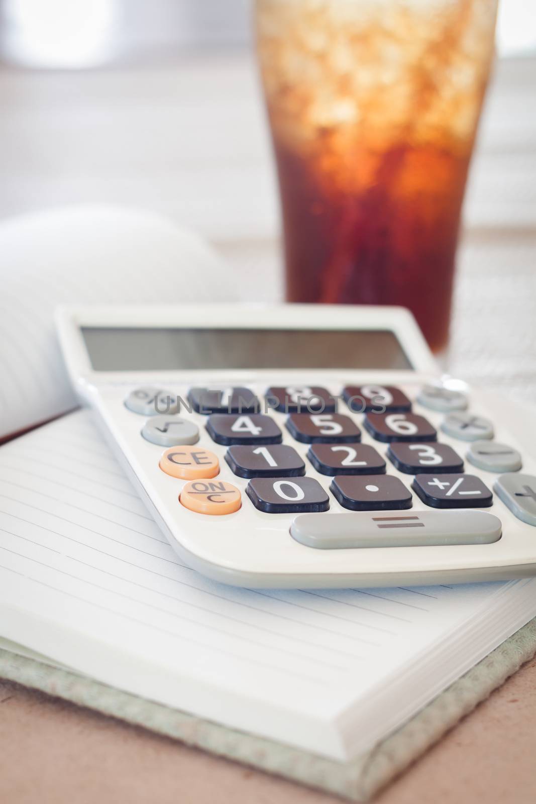 Calculator on blank notebook with a glass of cola, stock photo