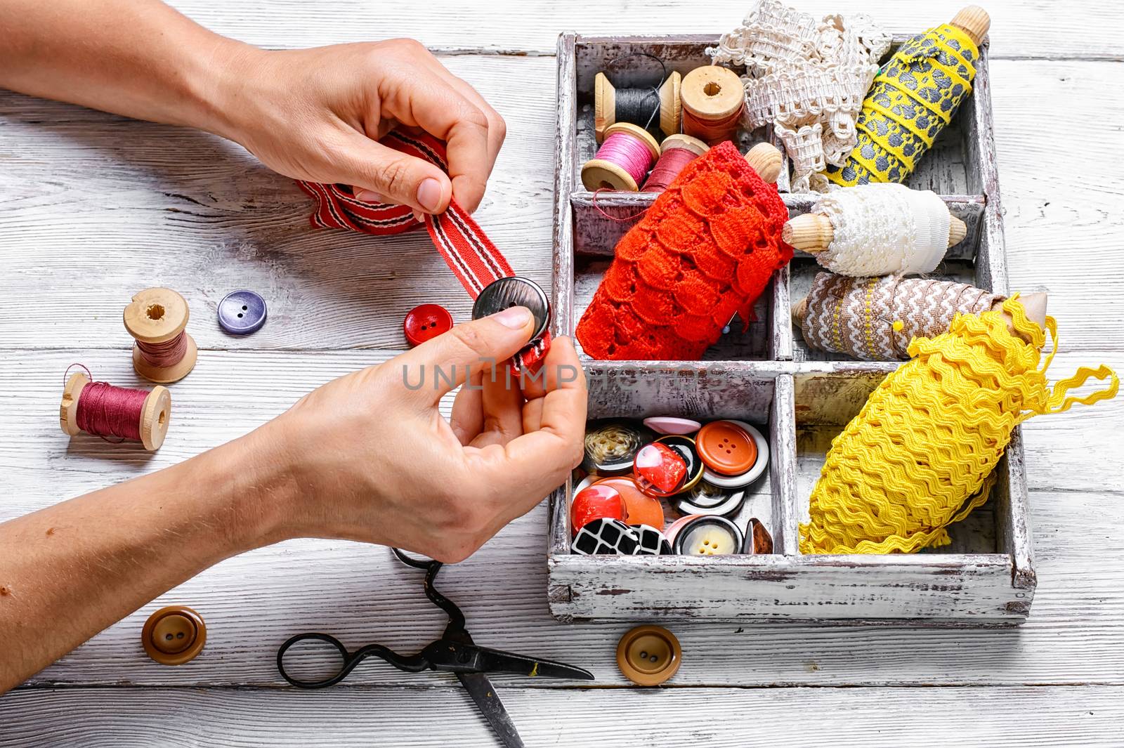 hands of tailor sewing accessories on background thread and buttons