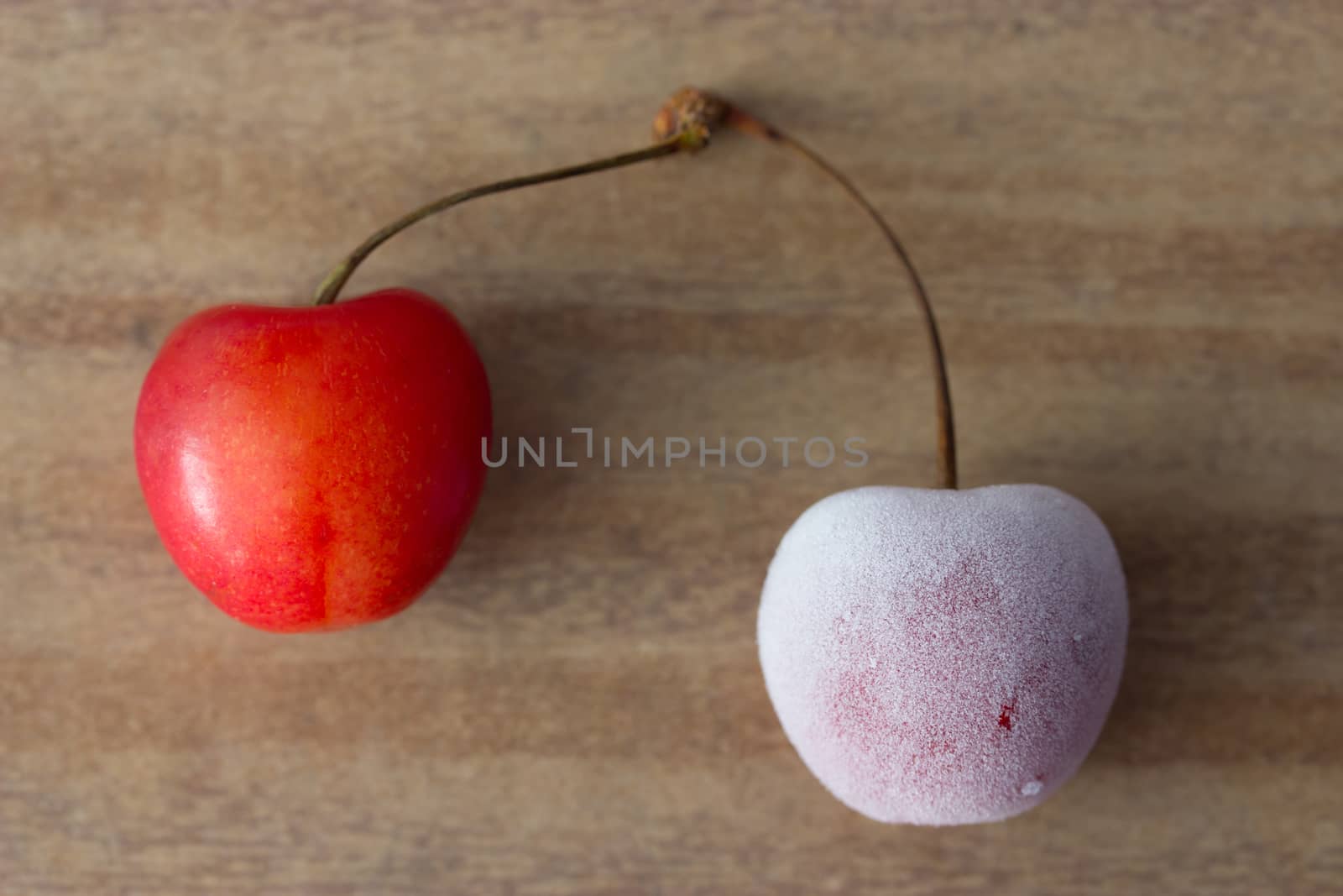two cherries: one frozen and one fresh