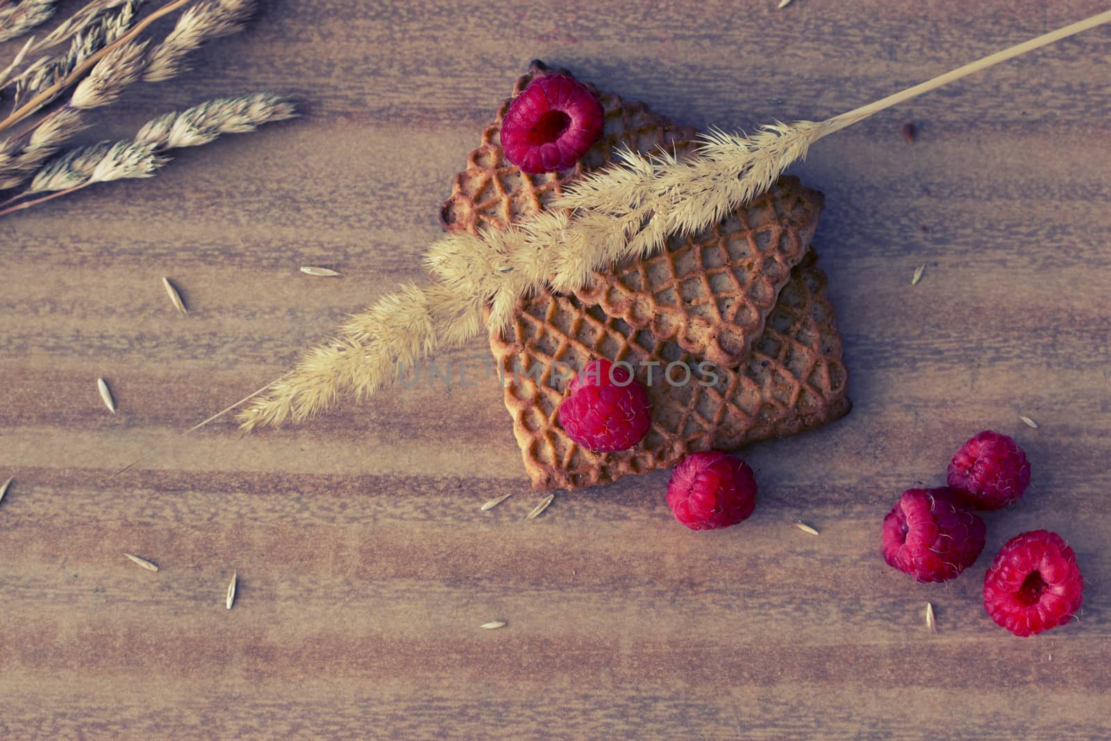 cookies with raspberries and ears on wooden table, toned