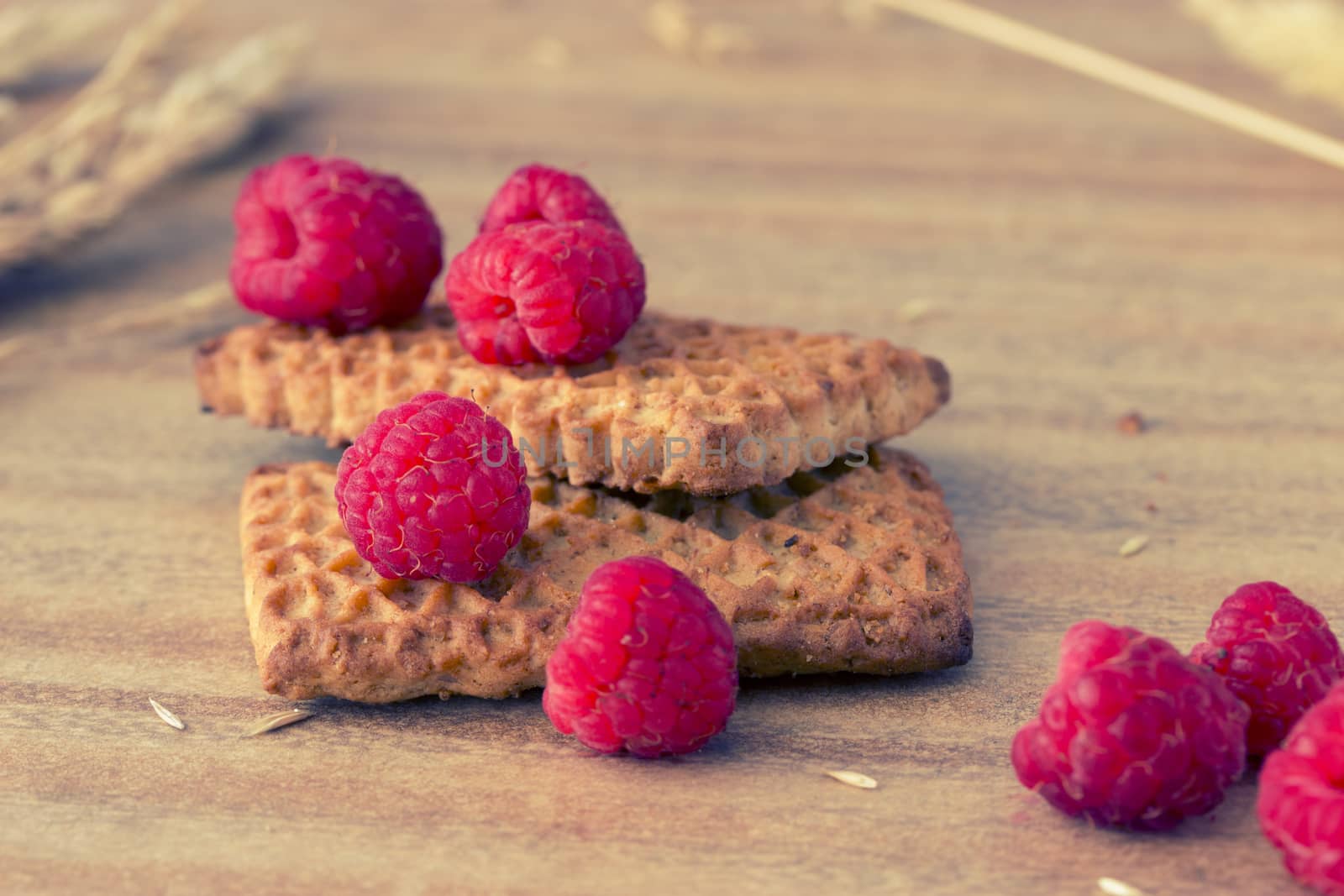 cookies with raspberries and ears on wooden table, toned