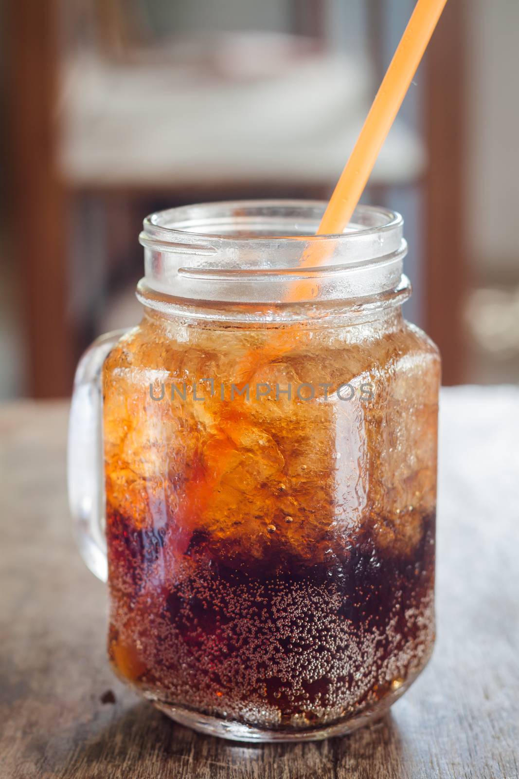 Glass of cola with ice on wooden table by punsayaporn