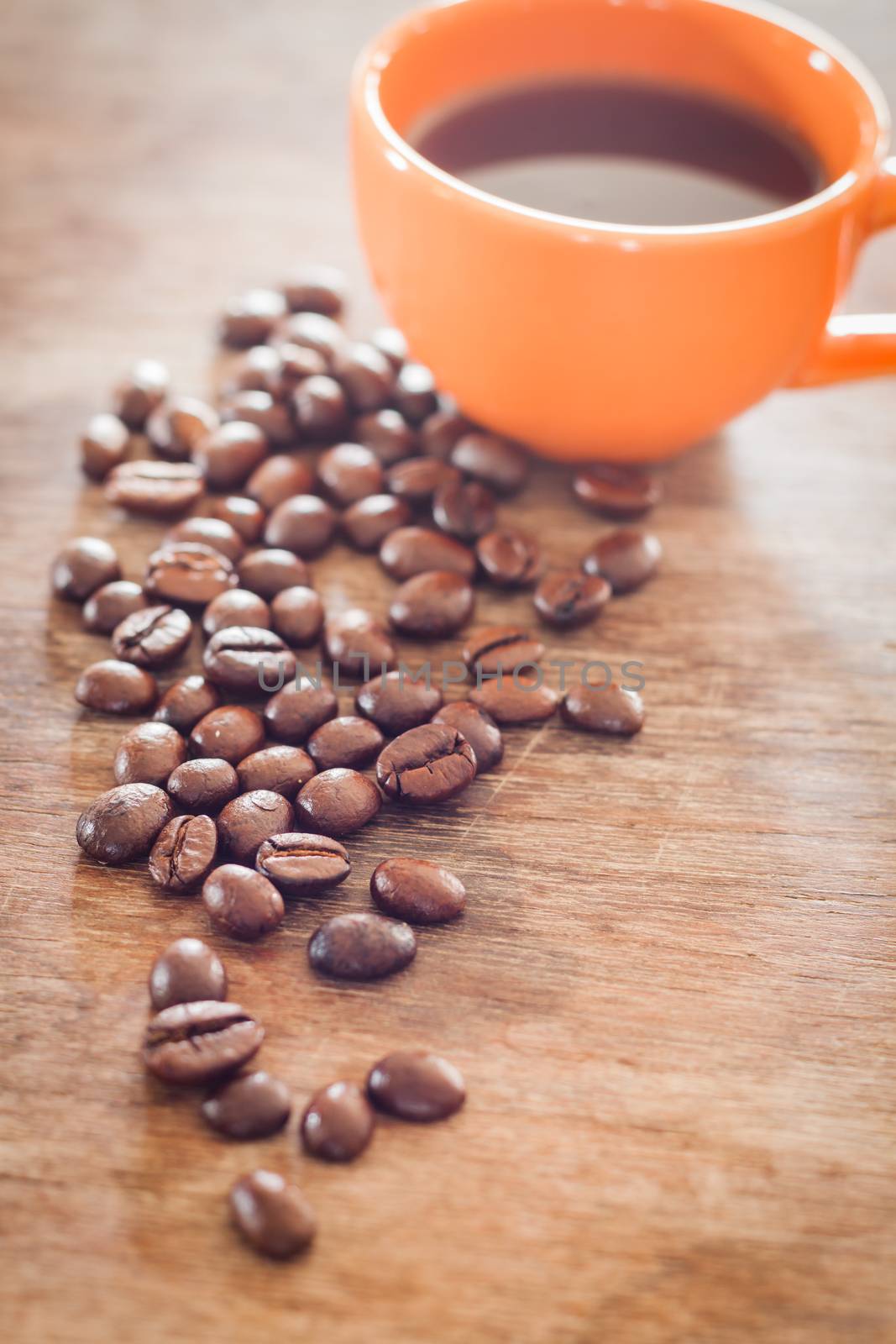 Coffee beans with coffee cup on wooden table, stock photo