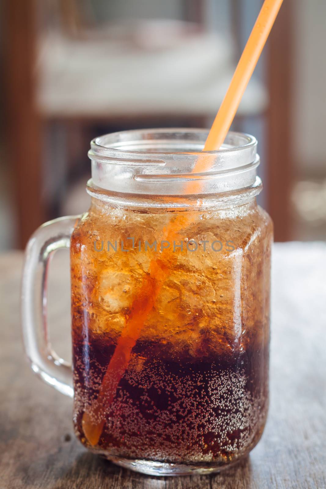 Glass of cola with ice on wooden table, stock photo