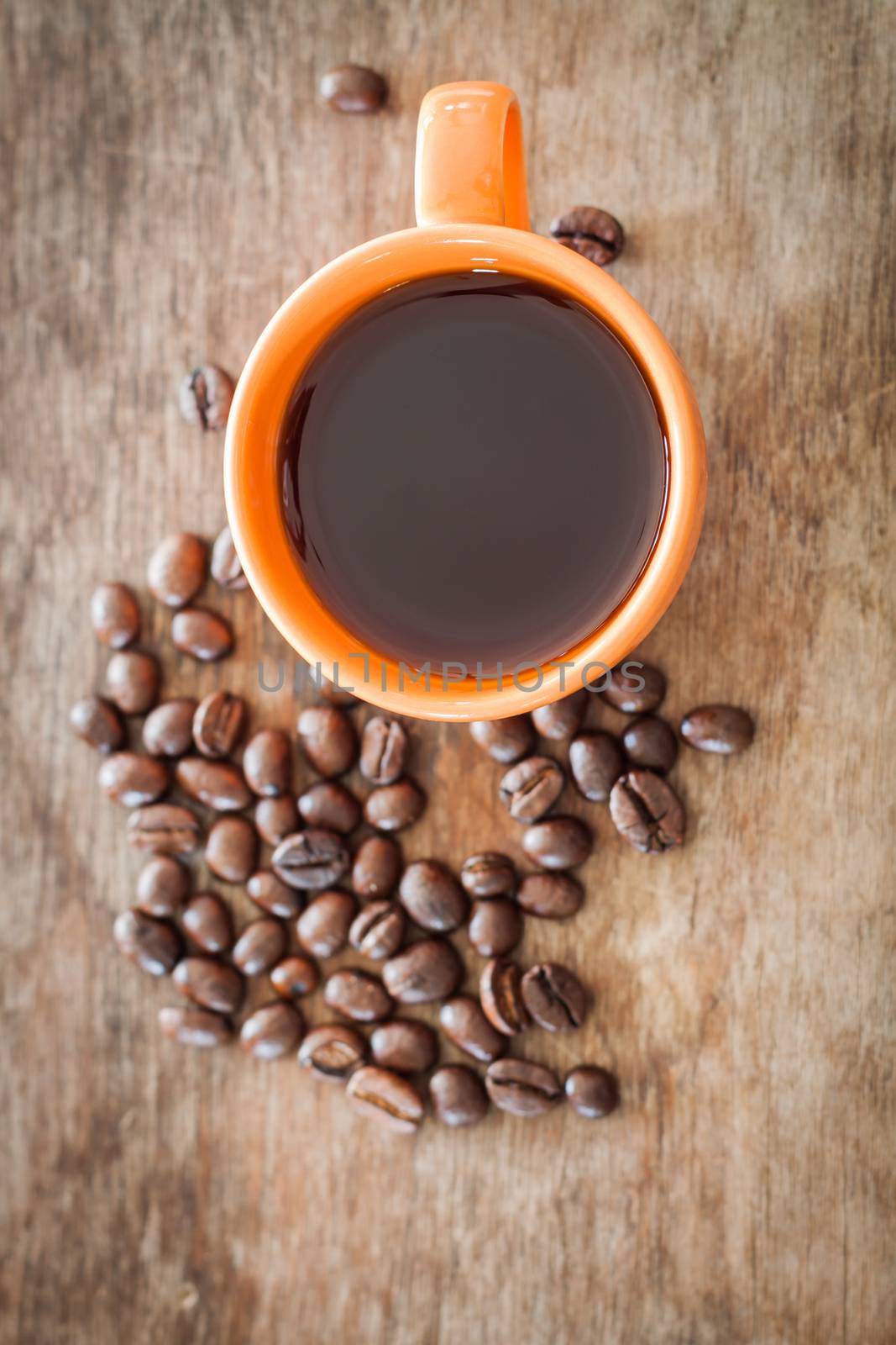 Coffee beans with coffee cup on wooden table, stock photo