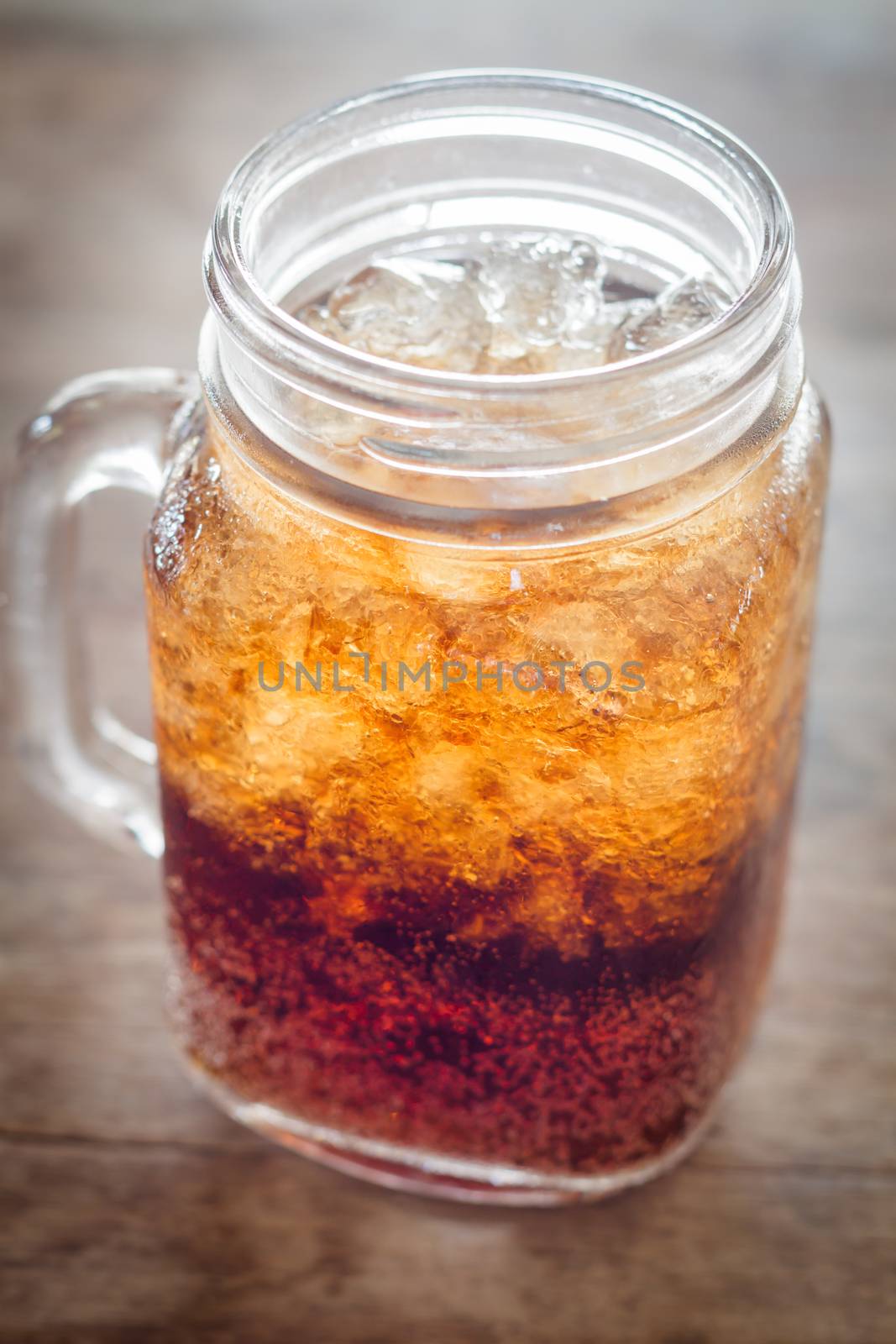 Glass of cola with ice on wooden table, stock photo