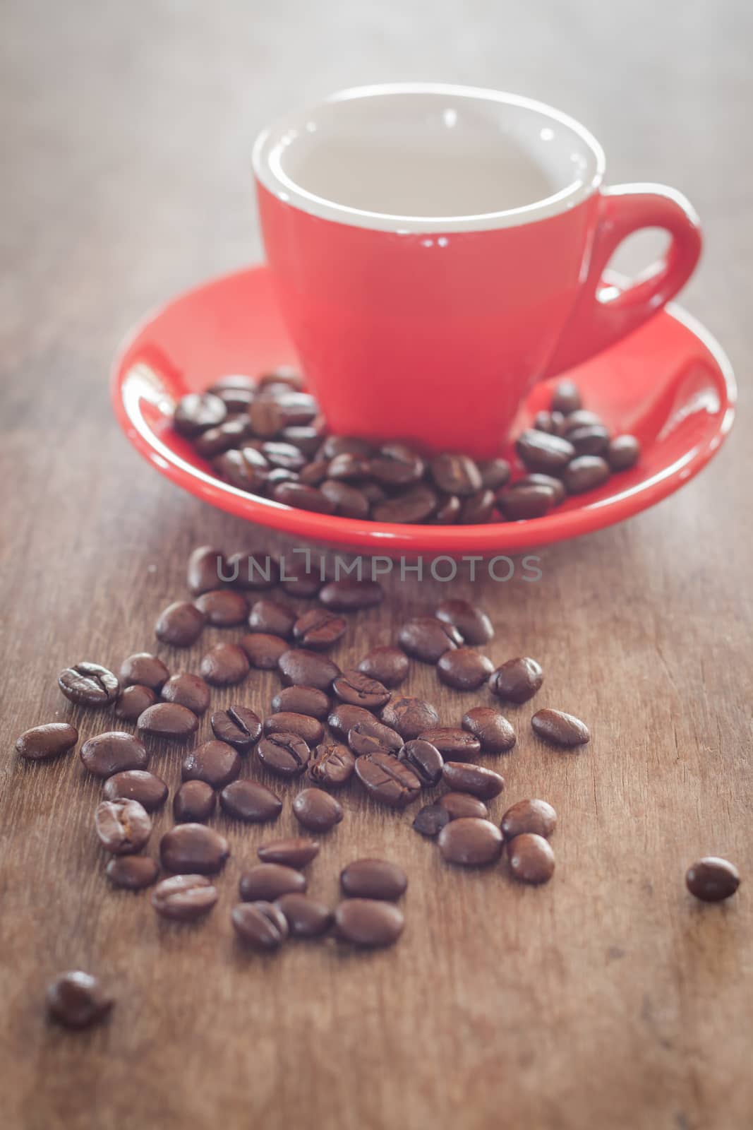 Red coffee cup with coffee beans on wooden table, stock photo