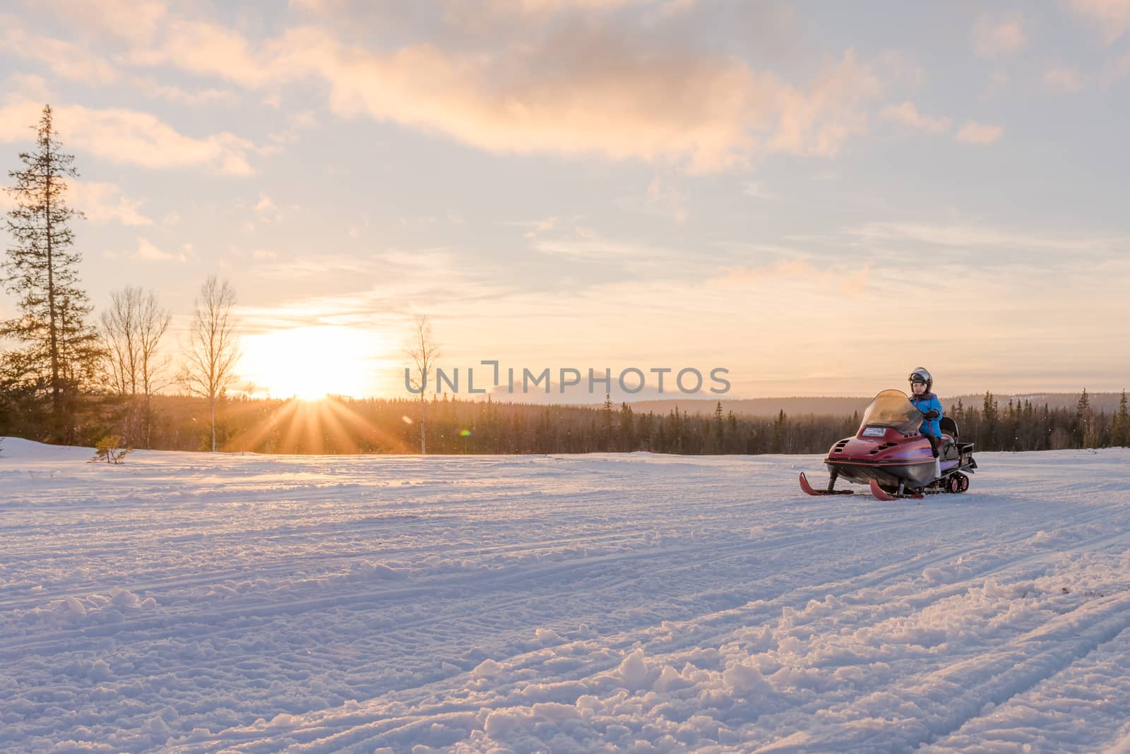 Woman riding snowmobile at sunset. Pure freedom.