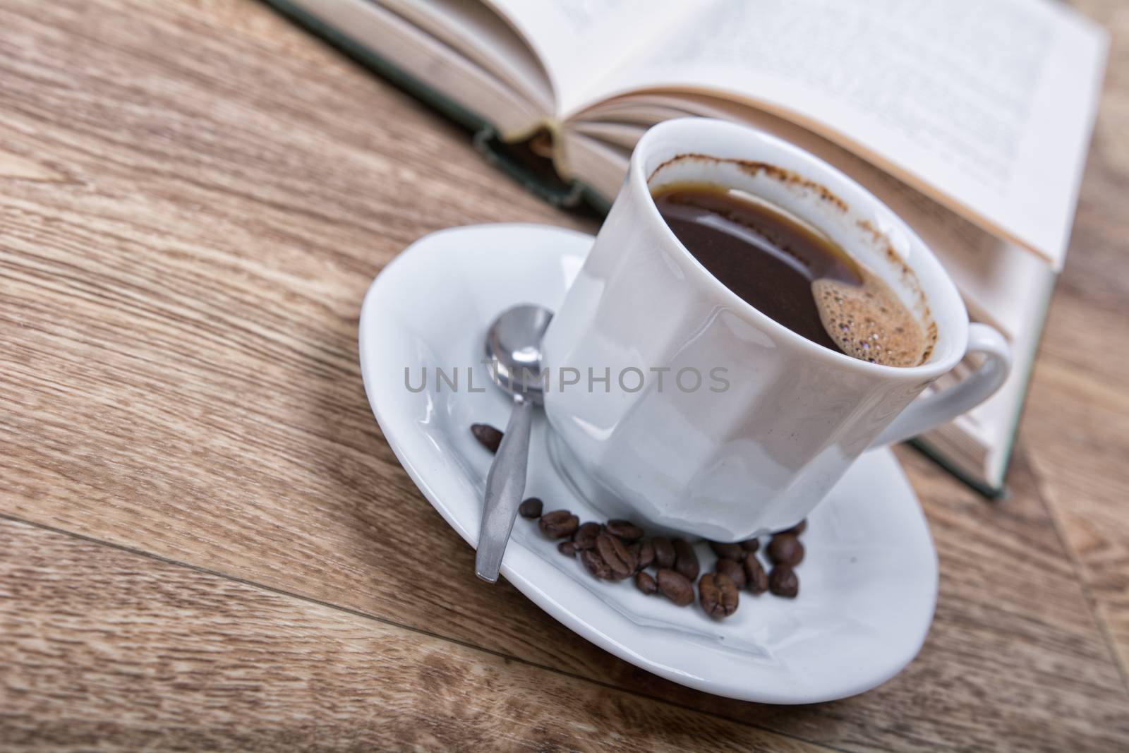 A cup of coffee with a book on a wooden background