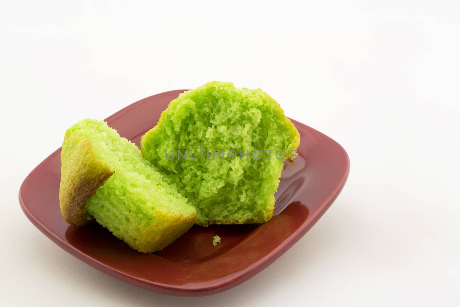 Vibrant green of sliced, fresh pistachio nut muffin.  Specialty baked good on red plate.  Copy space above on horizontal image. 