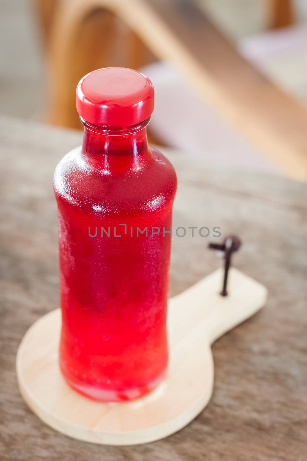 Red syrup in the bottle on wooden plate, stock photo