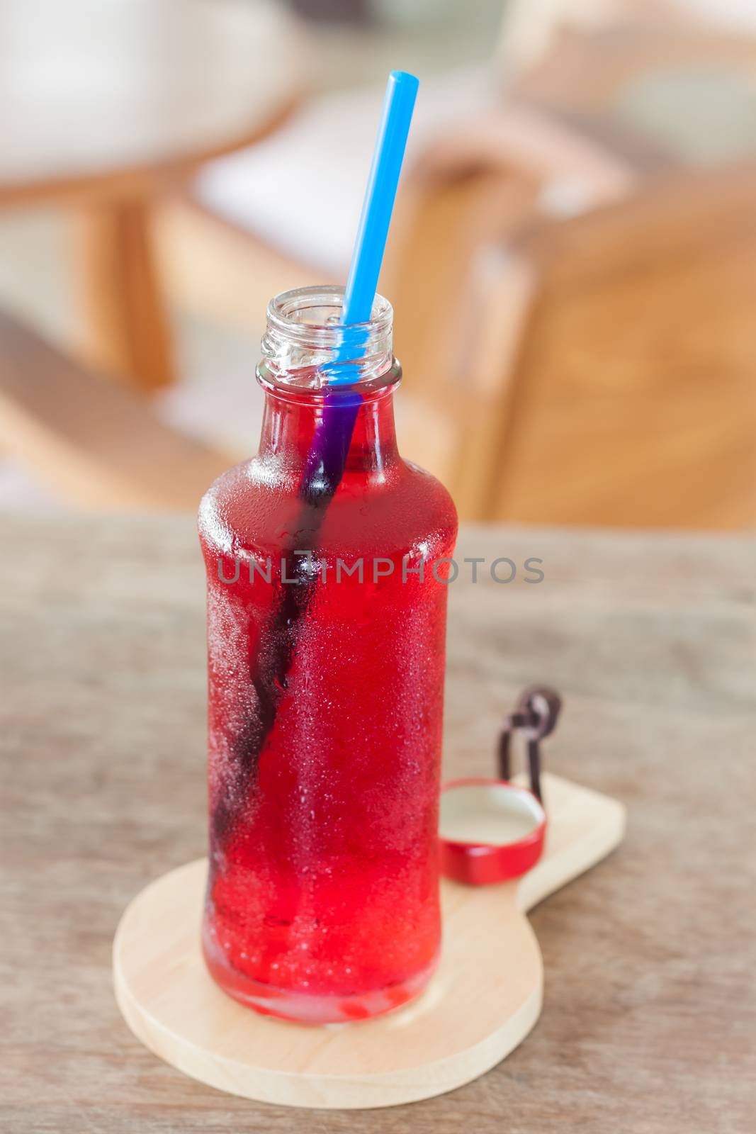 Red syrup in the bottle on wooden plate, stock photo