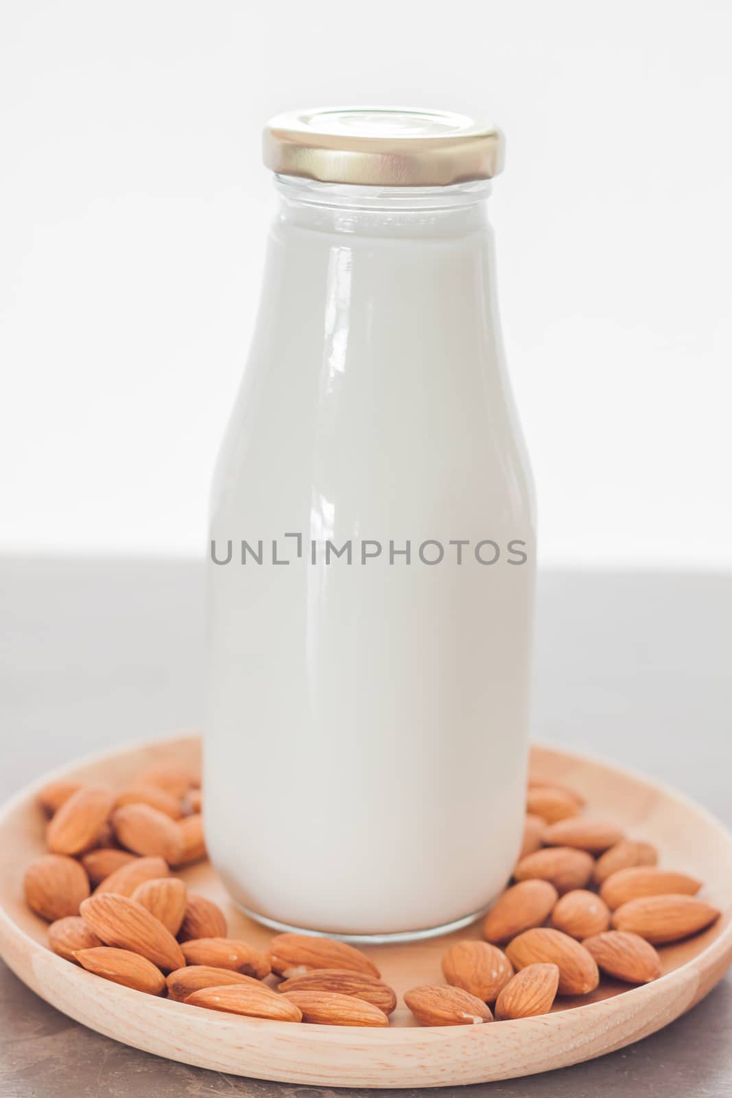 Almond nuts on wooden plate with milk by punsayaporn