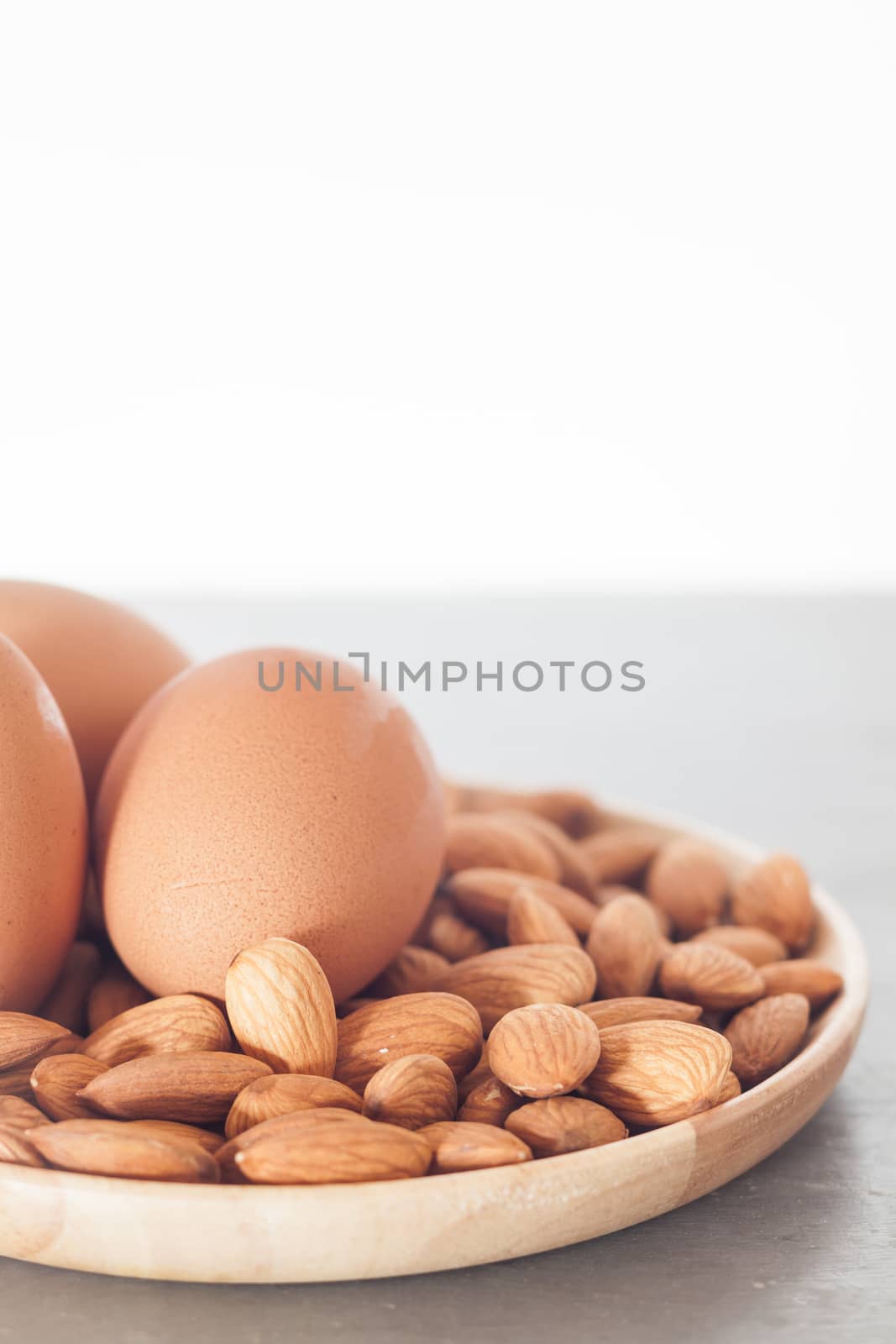 Almond nuts and eggs on wooden plate by punsayaporn