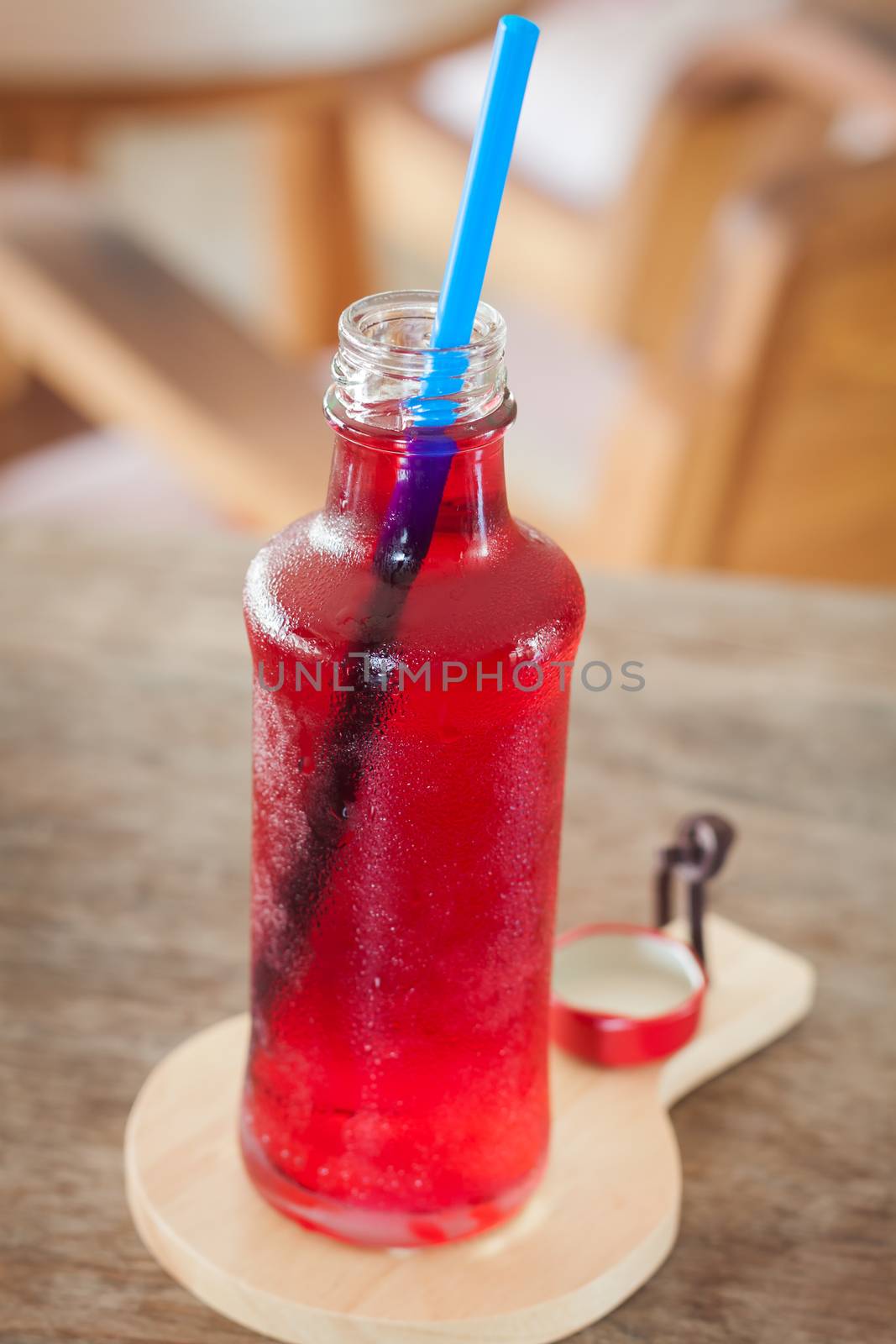 Red syrup in the bottle on wooden plate, stock photo