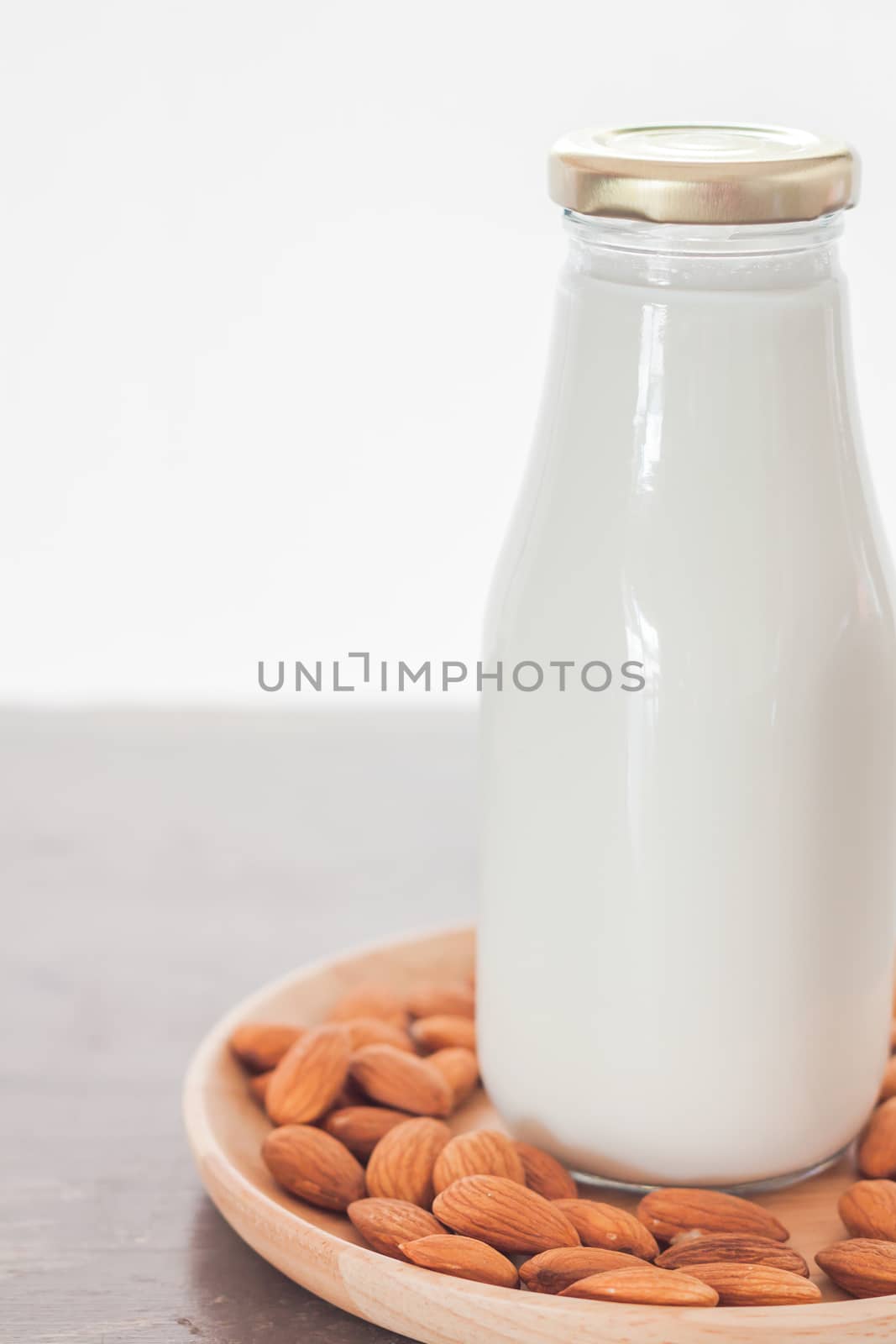 Almond nuts on wooden plate with milk, stock photo