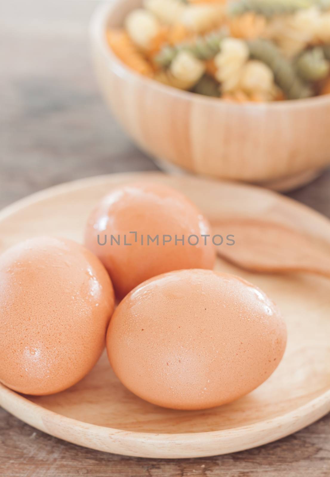 Fresh eggs on wooden plate with fusili by punsayaporn