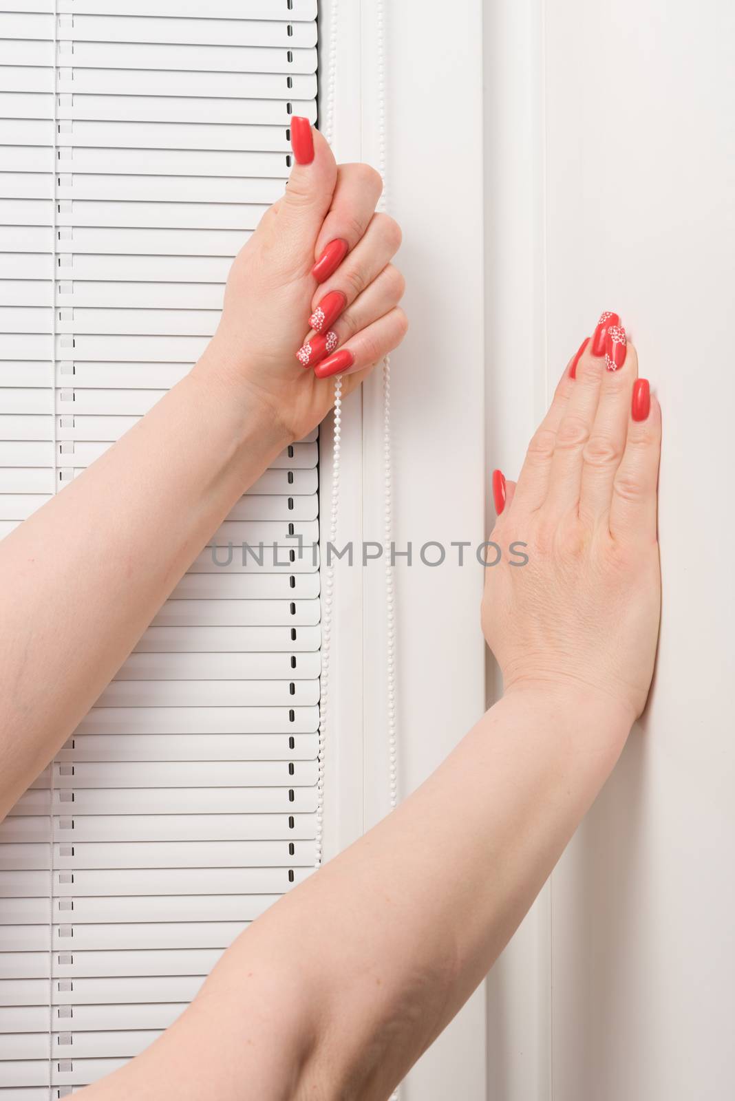 Female hands whith beauty manicure and blinds at window