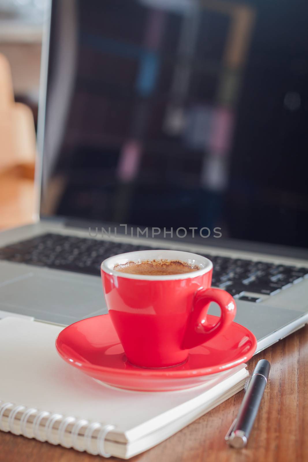 Red coffee cup with notepad and laptop, stock photo