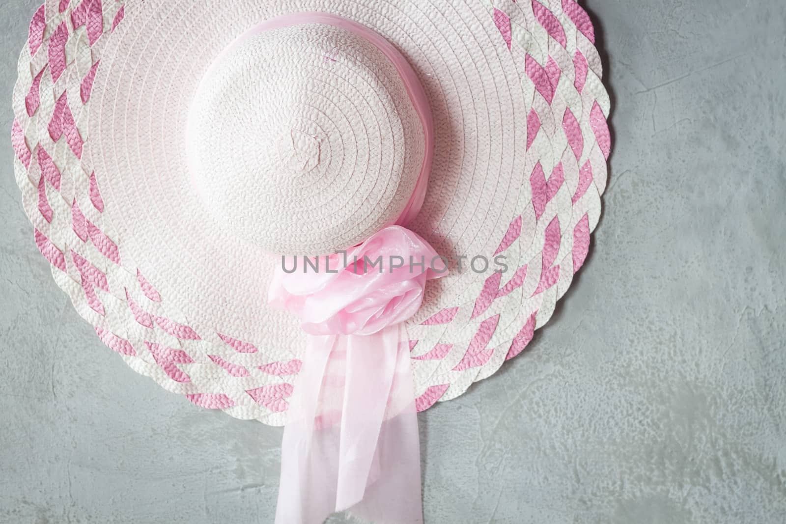 Pink hat with ribbon on grey background, stock photo