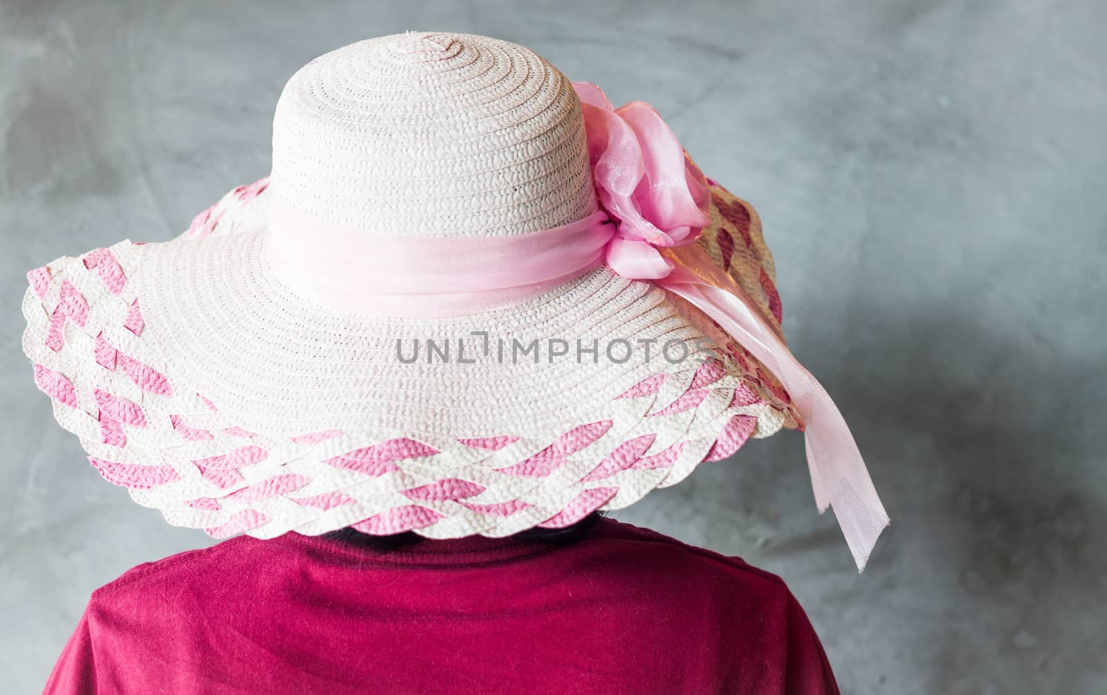 Woman with pink hat on grey background, stock photo