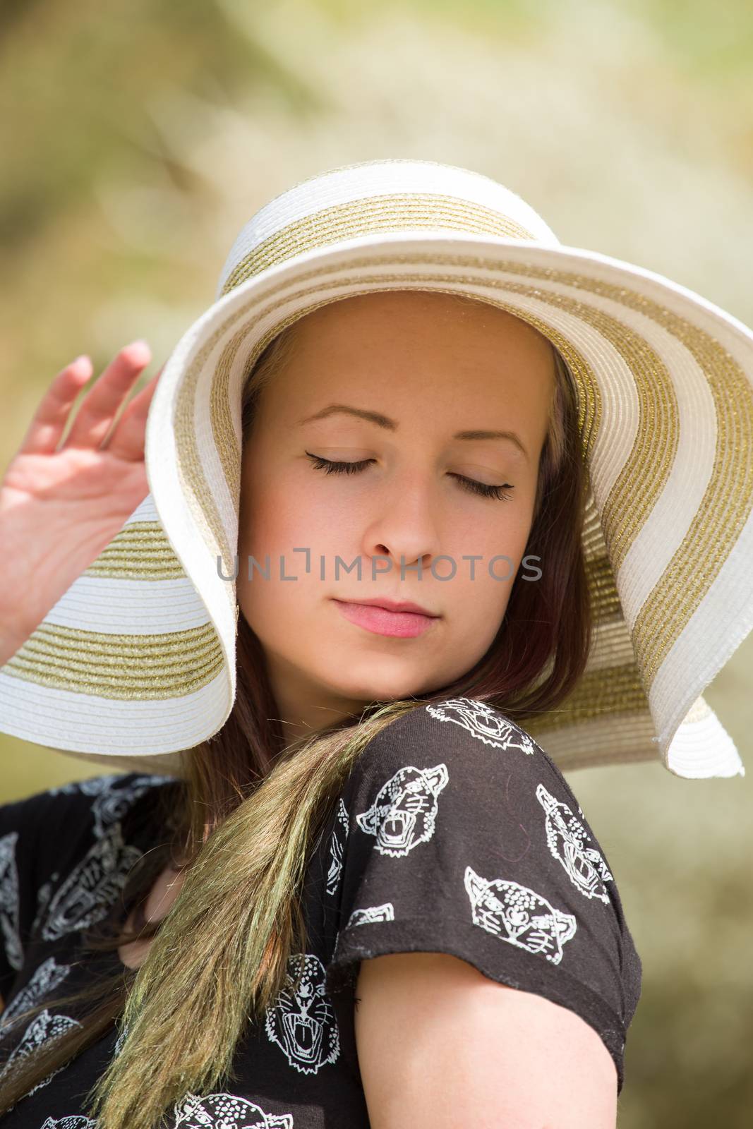 Portrait of cheerful fashionable woman in stylish hat and frock posing outdoor. Happy brunette girl with long hair in warm spring day