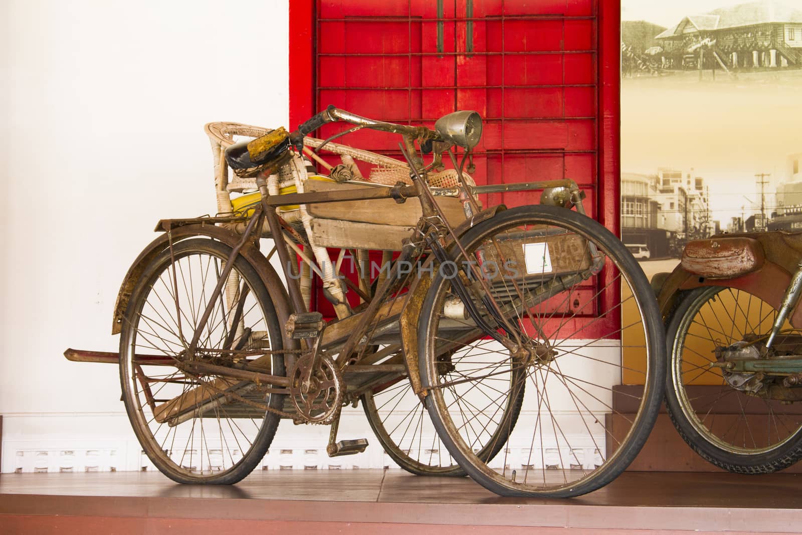 The ancient bicycles it have three whee, chair on bicyclel and behind have big red window.