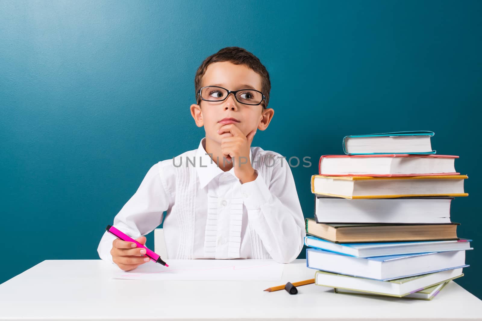 Cute little boy with books on the table, blue background