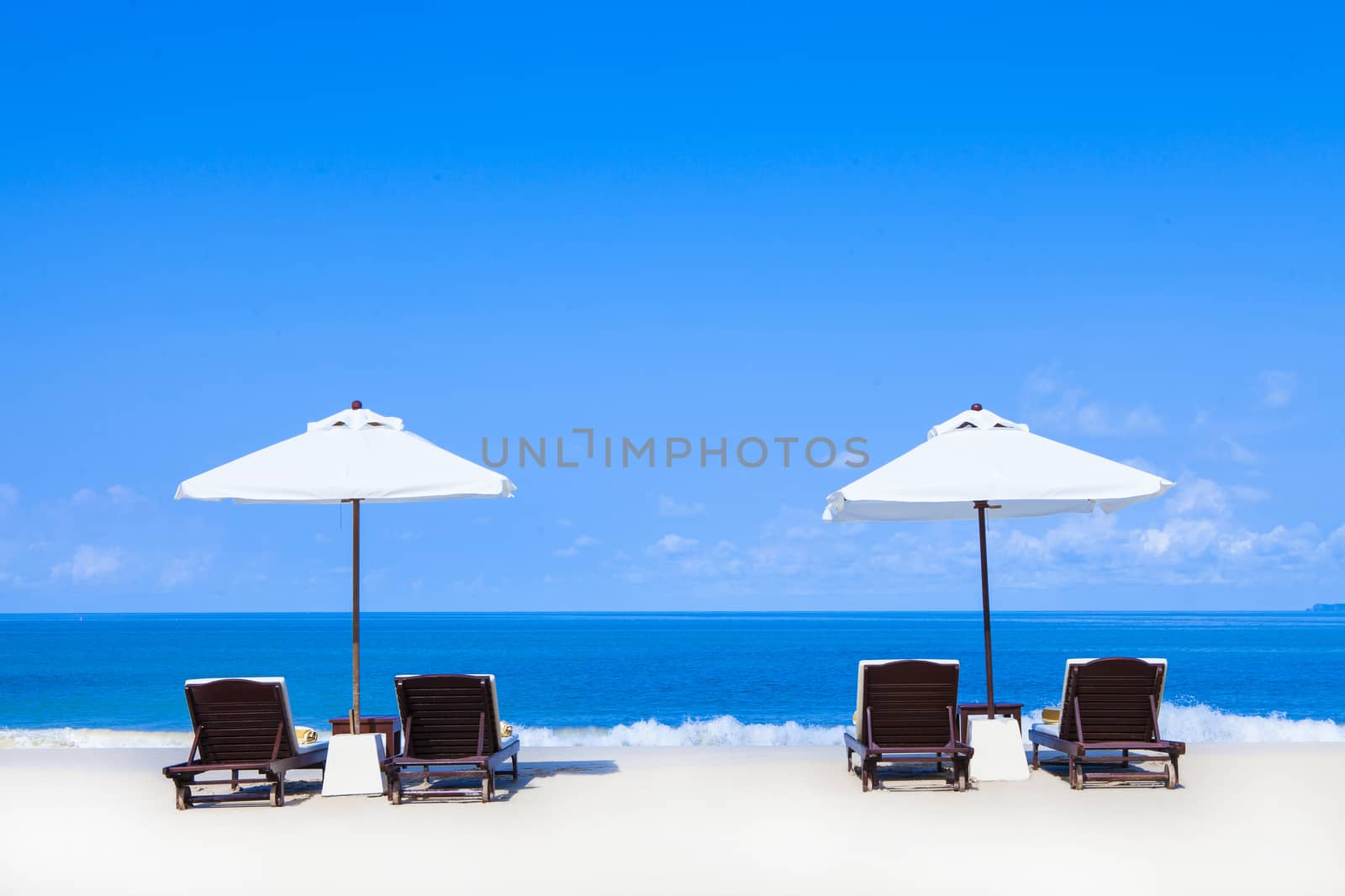 Beach chairs on the white sand beach with cloudy blue sky and sun, Koh Lanta Krabi Thailand.