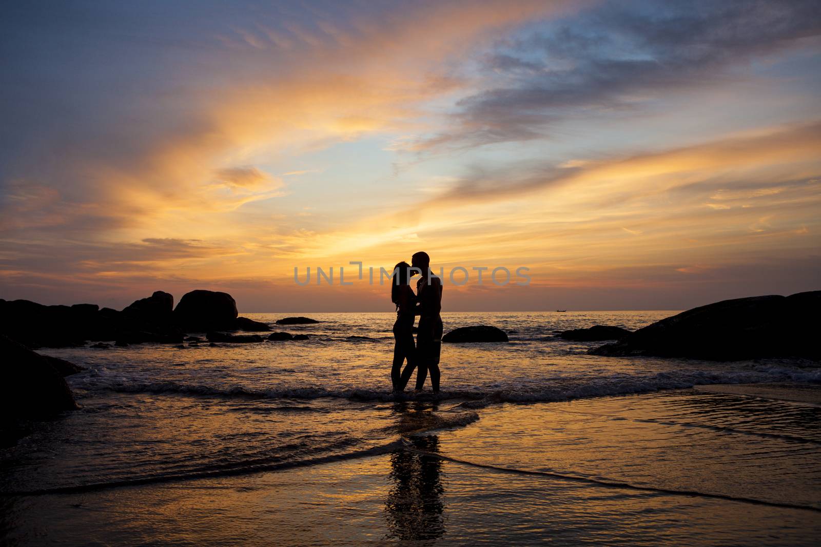 Couple kissing on the beach with a beautiful sunset in background