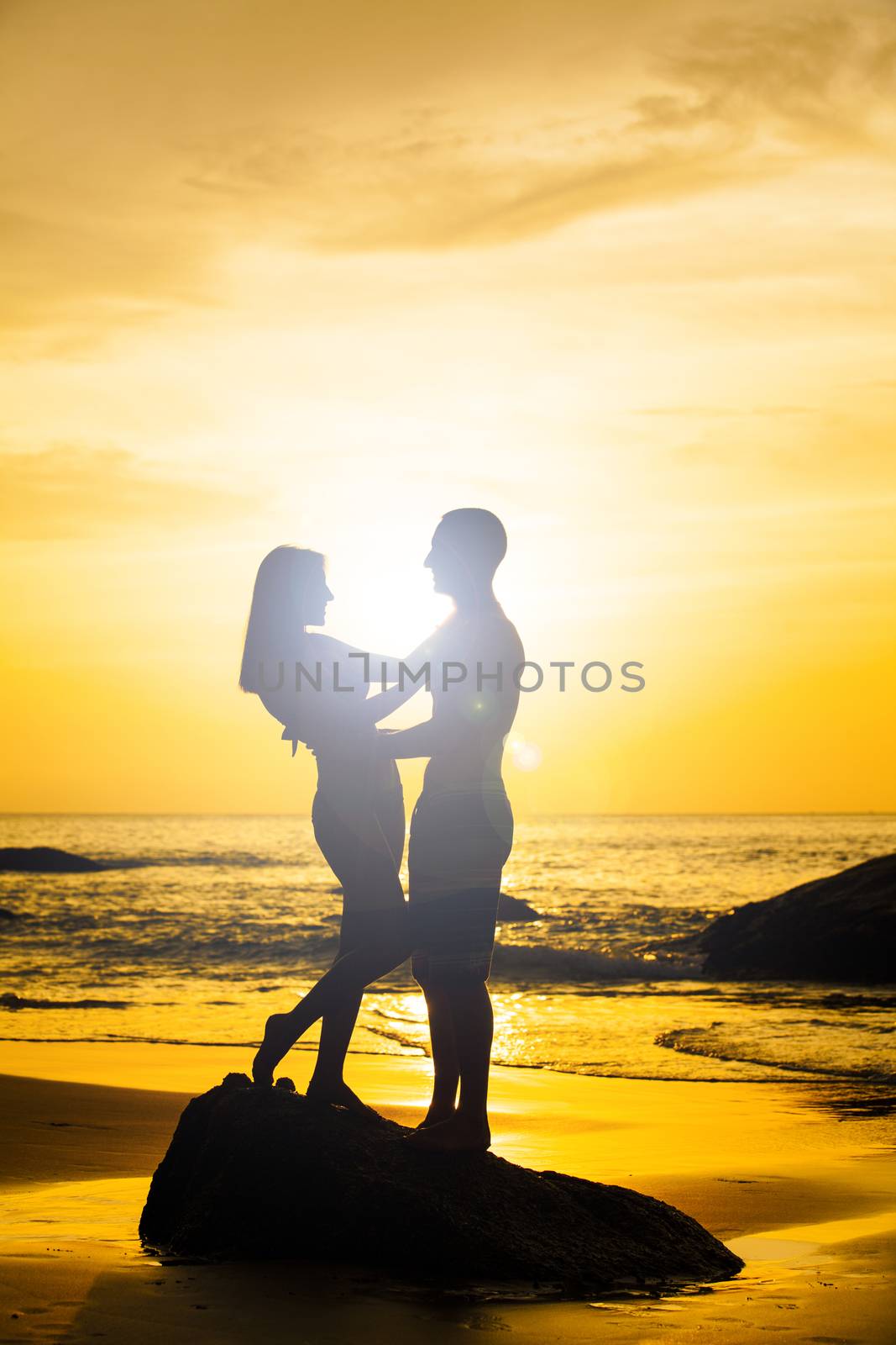 Couple kissing on the beach with a beautiful sunset in background