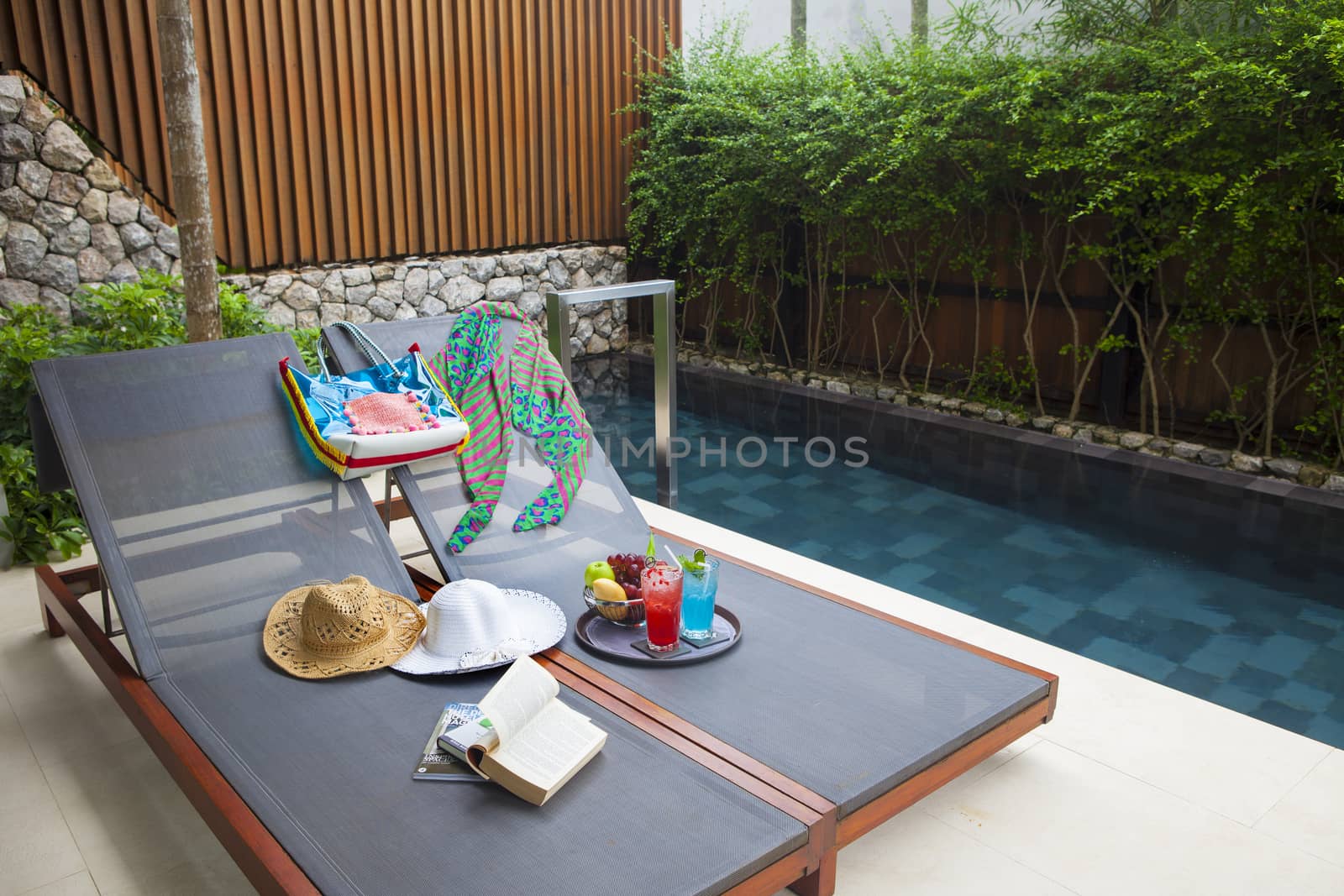 Reclining chair with bag, hat, bag, book, nectar and fruit eat when resting.
