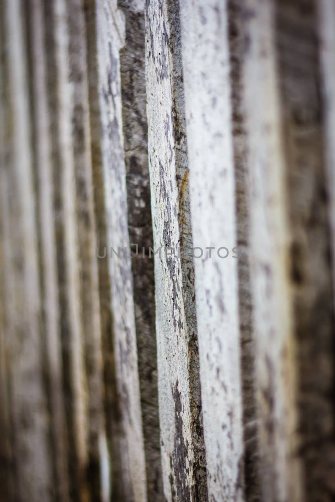 Detail view along an old  picket wooden fence with selective focus