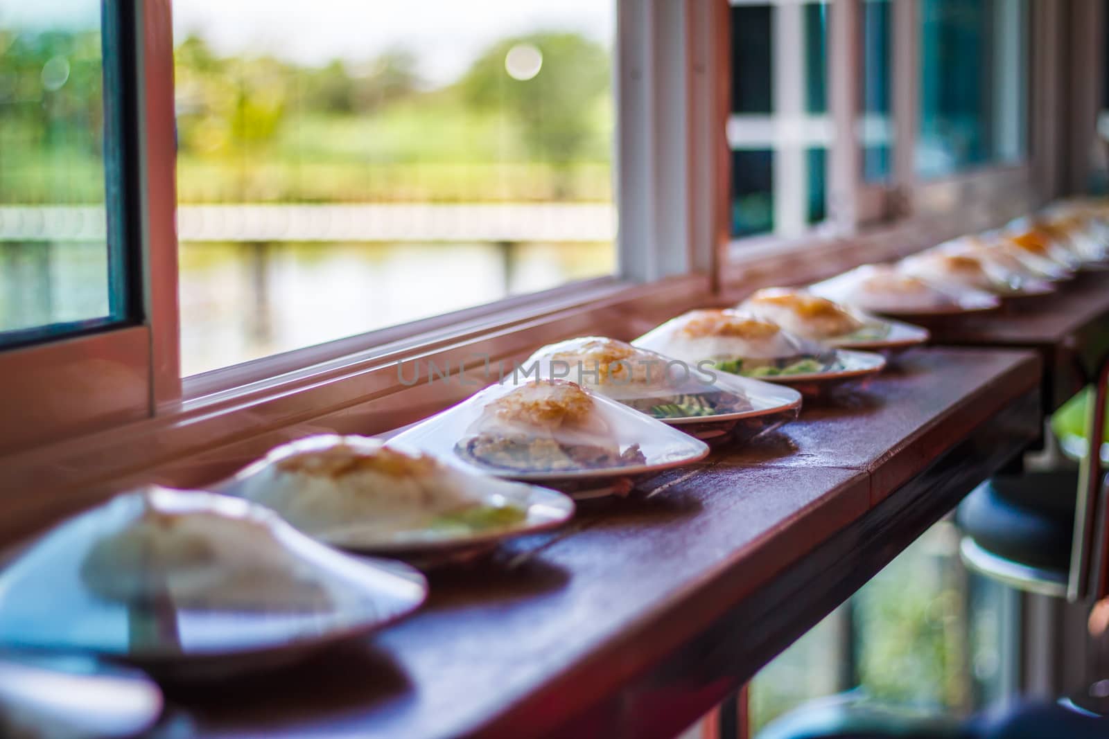 Rice topped with stir-fried chicken, basil and fried egg, fried stir basil with minced chicken on near window