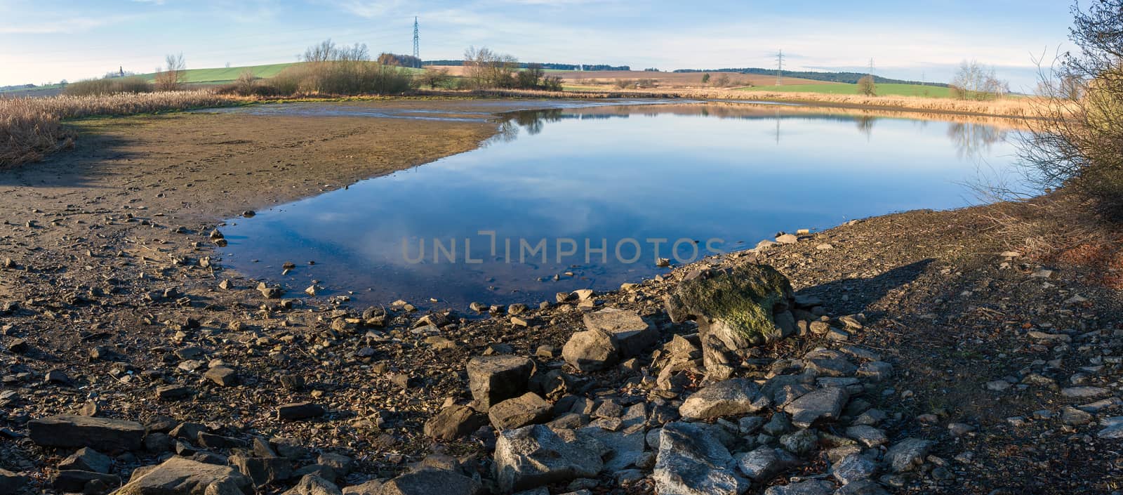 drained pond in winter against blue sky, rural scene, landscape