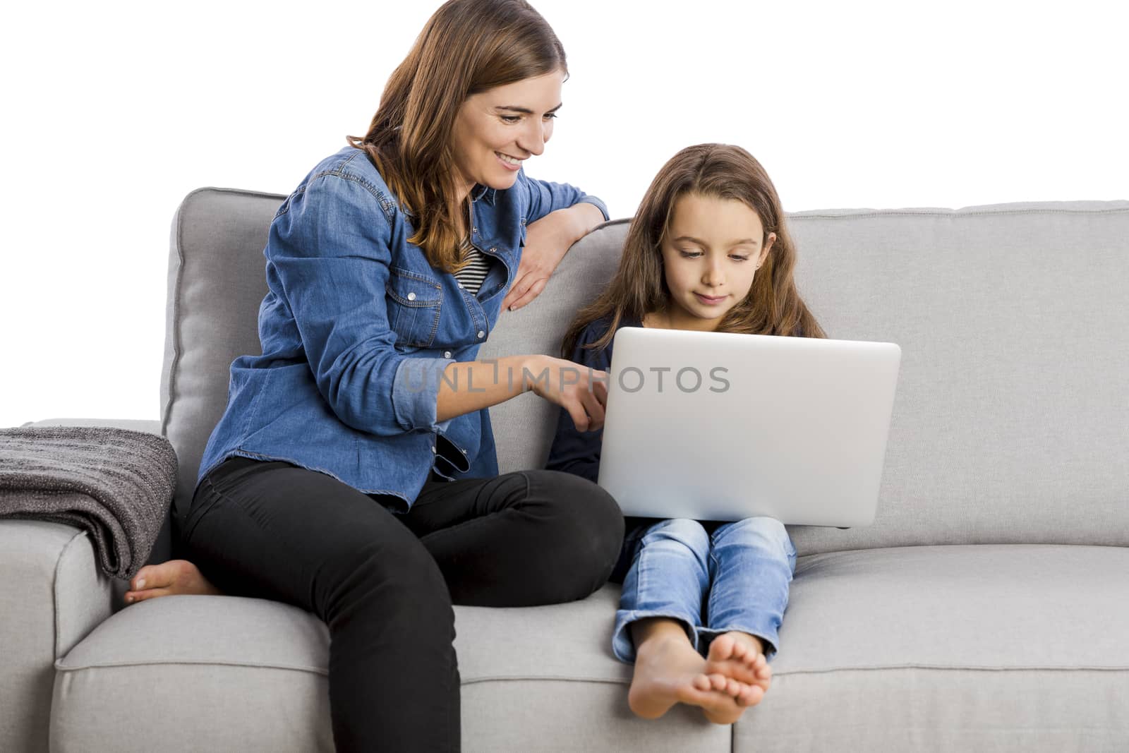 Mother teaching her little daughter working with a laptop