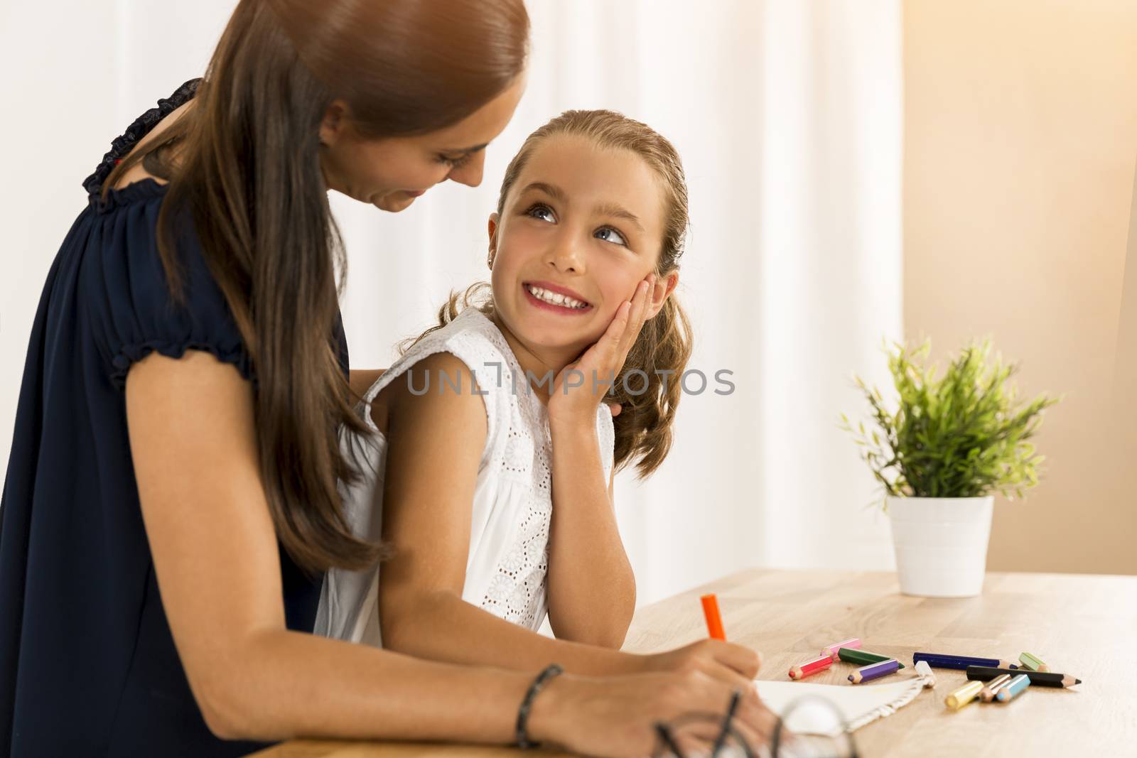 Mother helping her little daughter making drawings