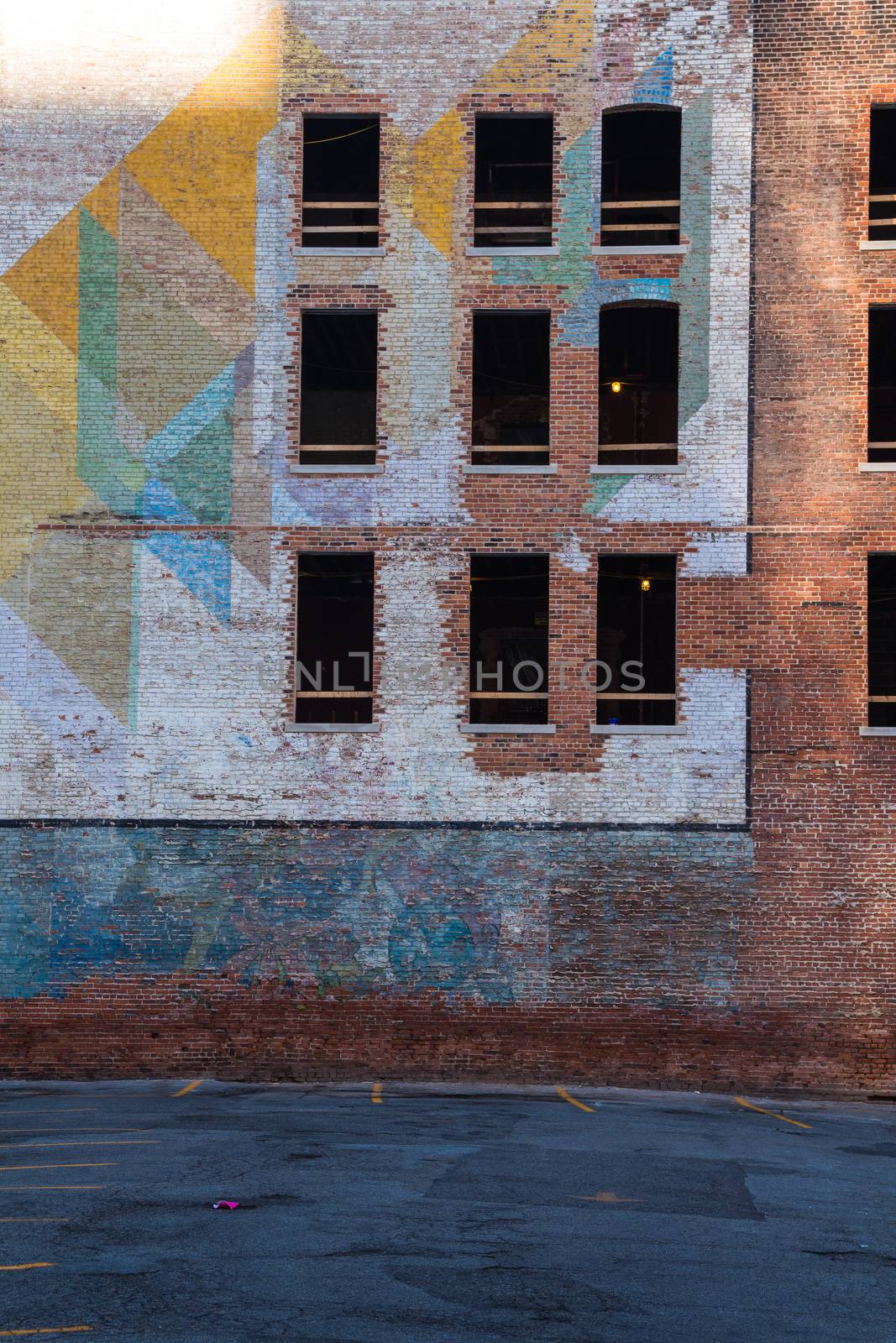 Old abandoned building in the downtown of Detroit. Facade made of bricks, partly with a colorful painting. Broken windows.