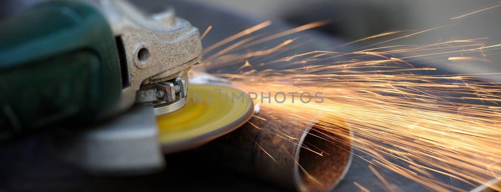 Worker cutting metal with grinder by byrdyak